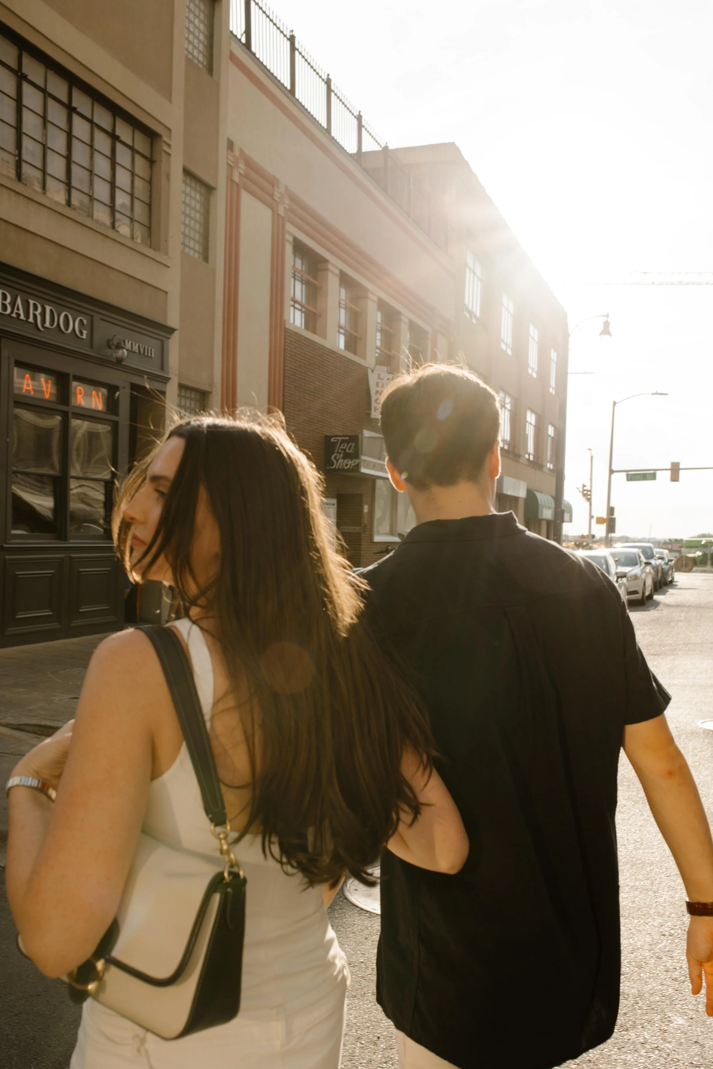 Couple walking into golden light with soft sun flare during new york city engagement photos in a downtown setting