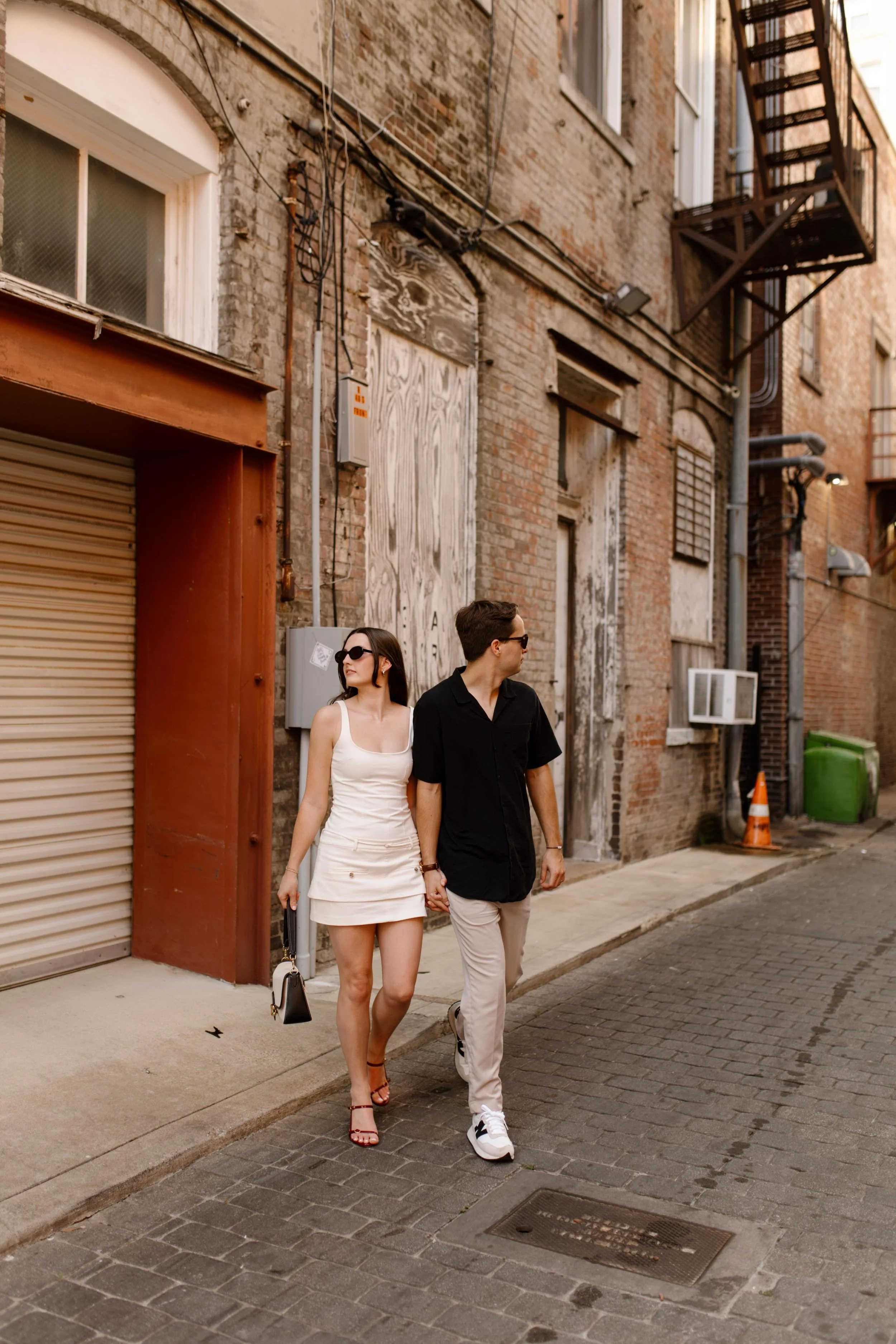 Couple walking through an alley with textured brick walls during new york city engagement photos with a candid feel