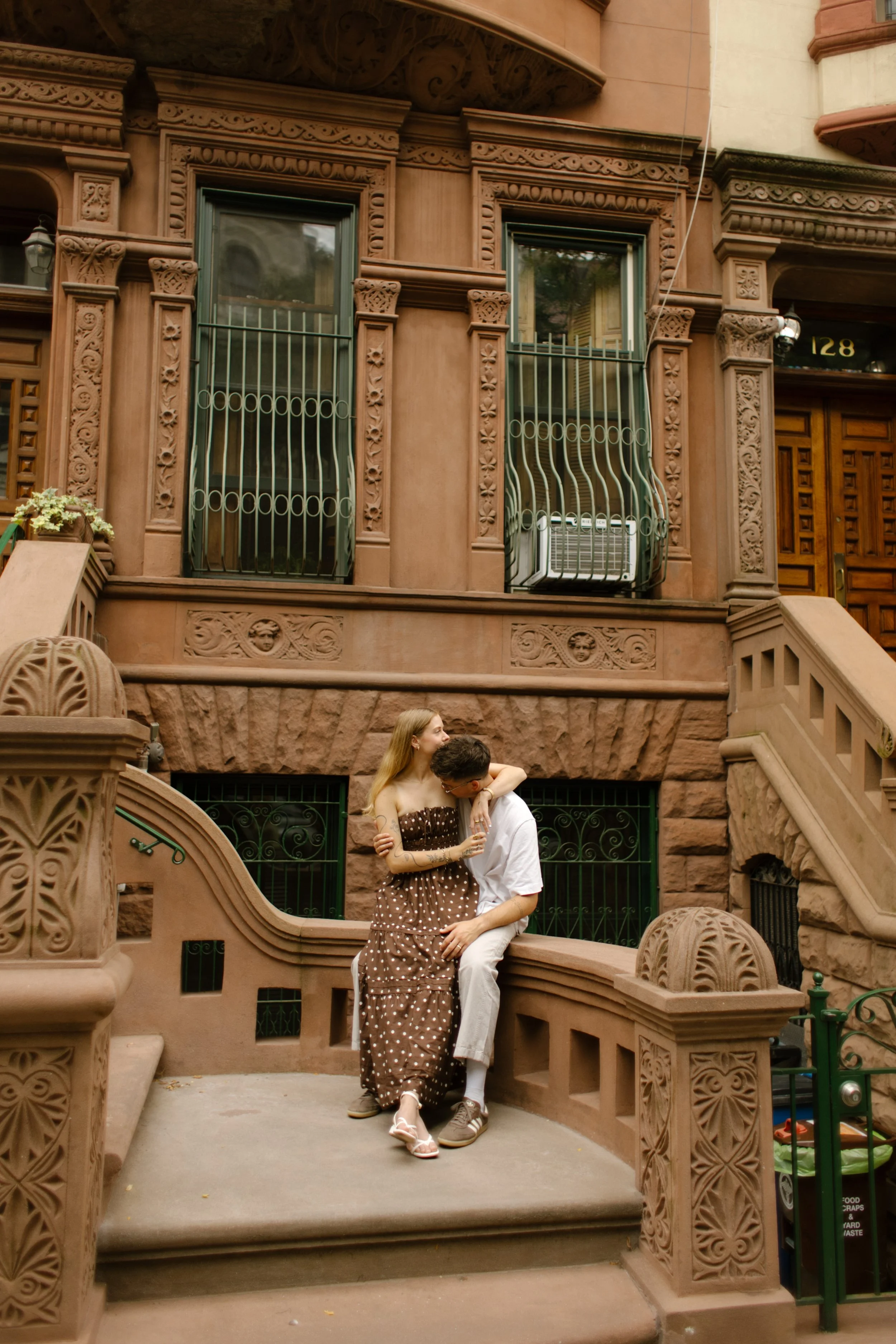 Couple sitting together on classic brownstone steps in New York, sharing a quiet, intimate moment