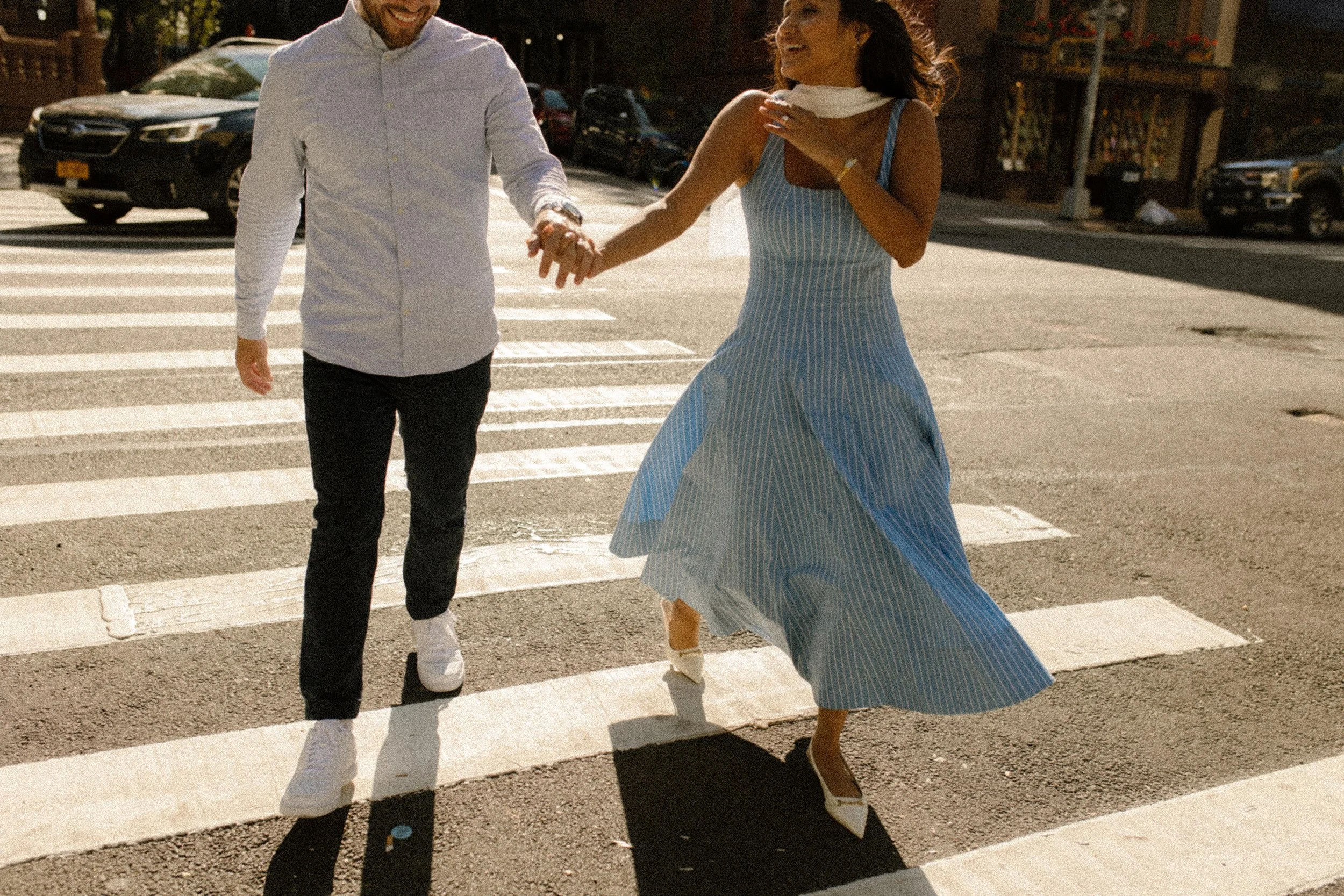 Newly engaged couple running across crosswalk together in New York.
