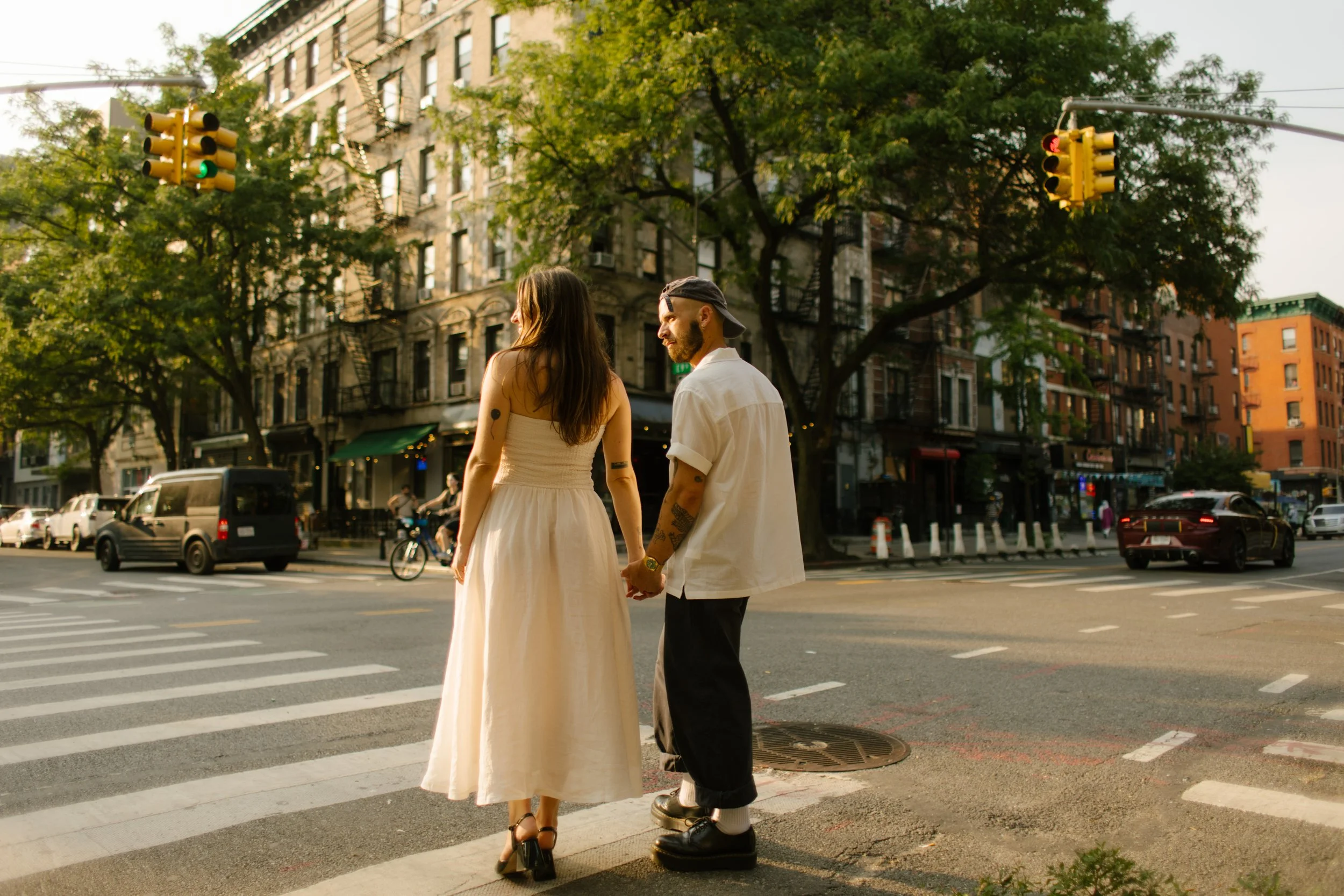 New York engagement photographer documenting a couple holding hands at a quiet Manhattan street corner at golden hour.
