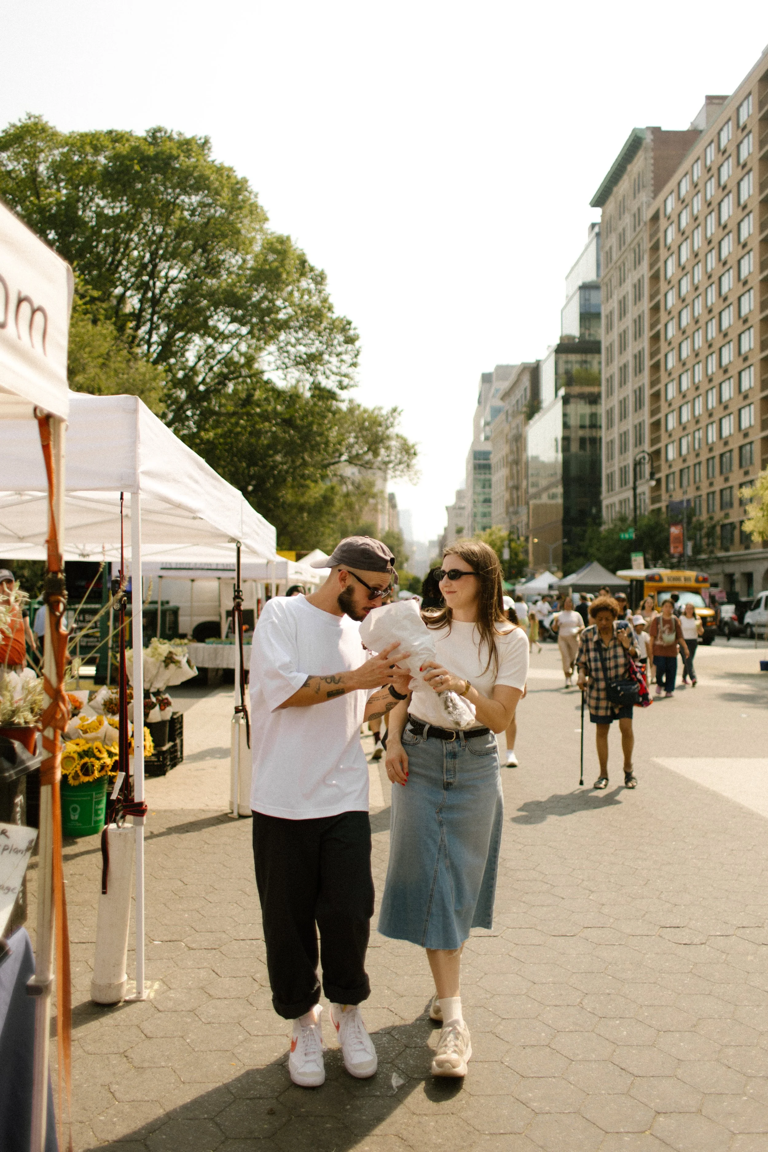 New York engagement photographer capturing a couple strolling through a Manhattan farmers market on a sunny afternoon.