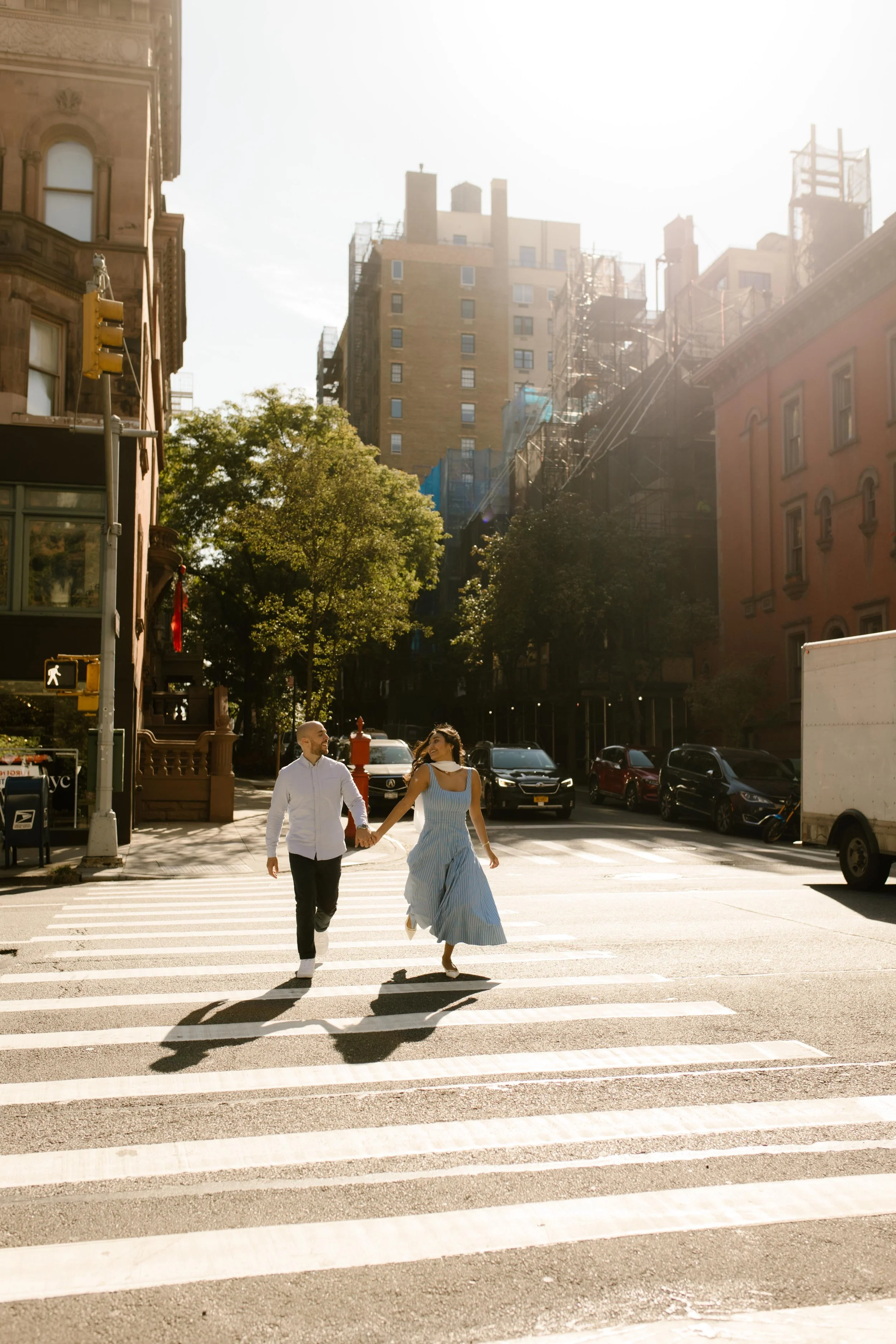 New York engagement photographer capturing a couple crossing a Manhattan street together in warm golden light.