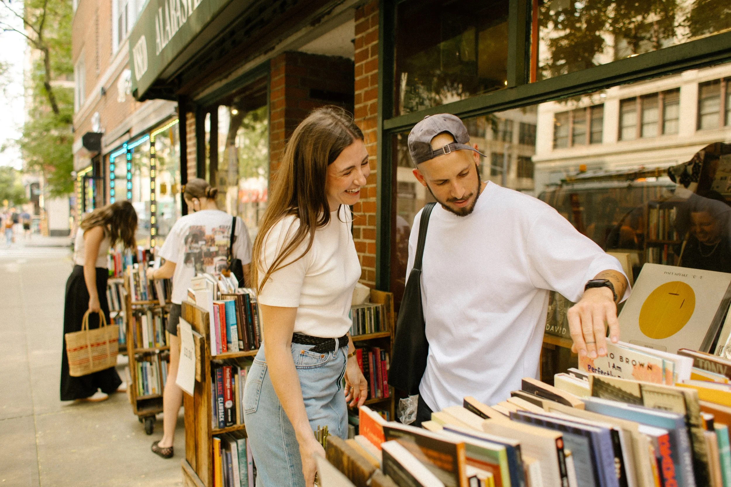 Couple browsing books together outside a neighborhood bookstore during a candid New York City engagement shoot.