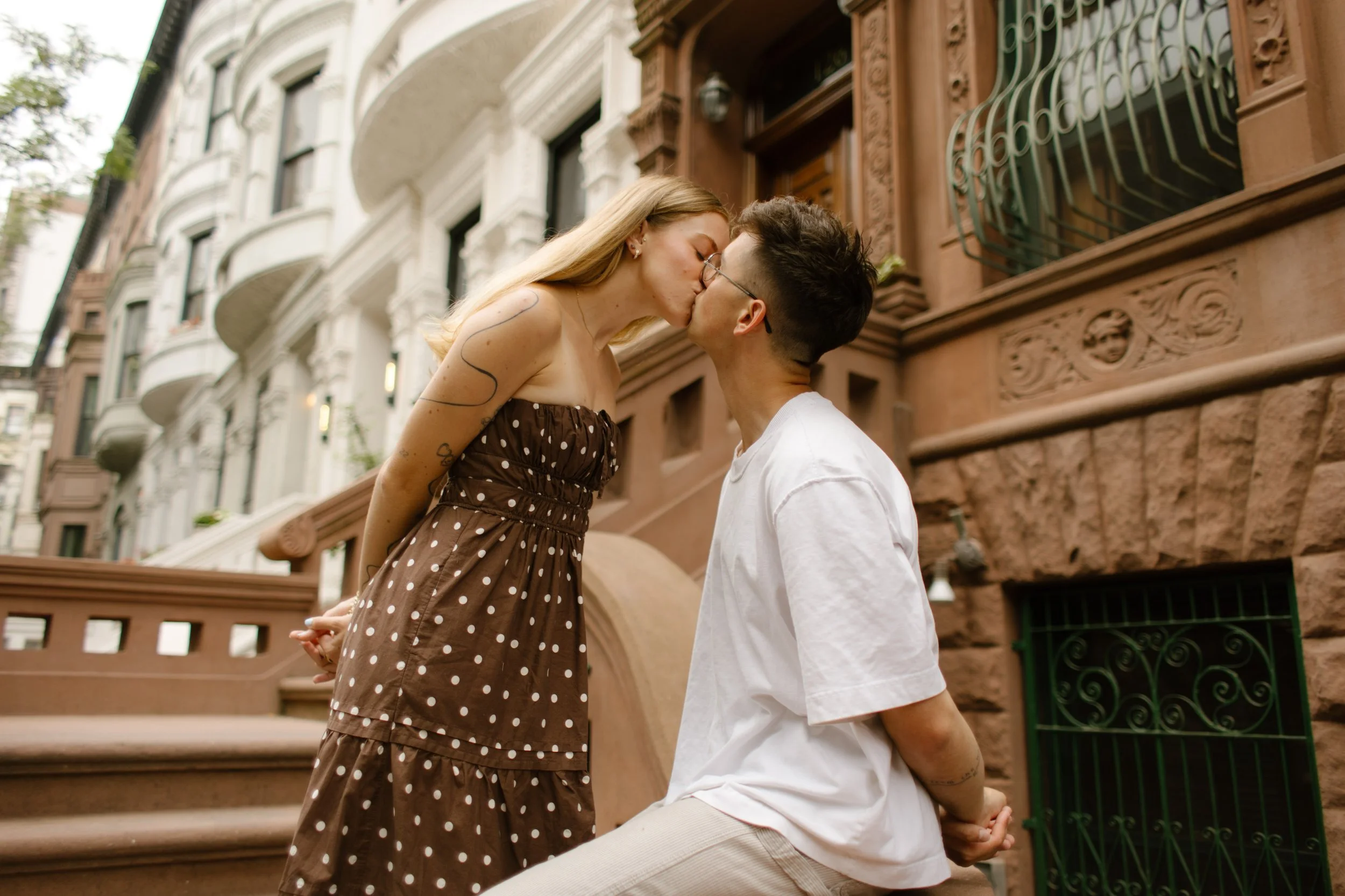 Couple kissing on a Brooklyn brownstone stoop during a casual and intimate engagement session.