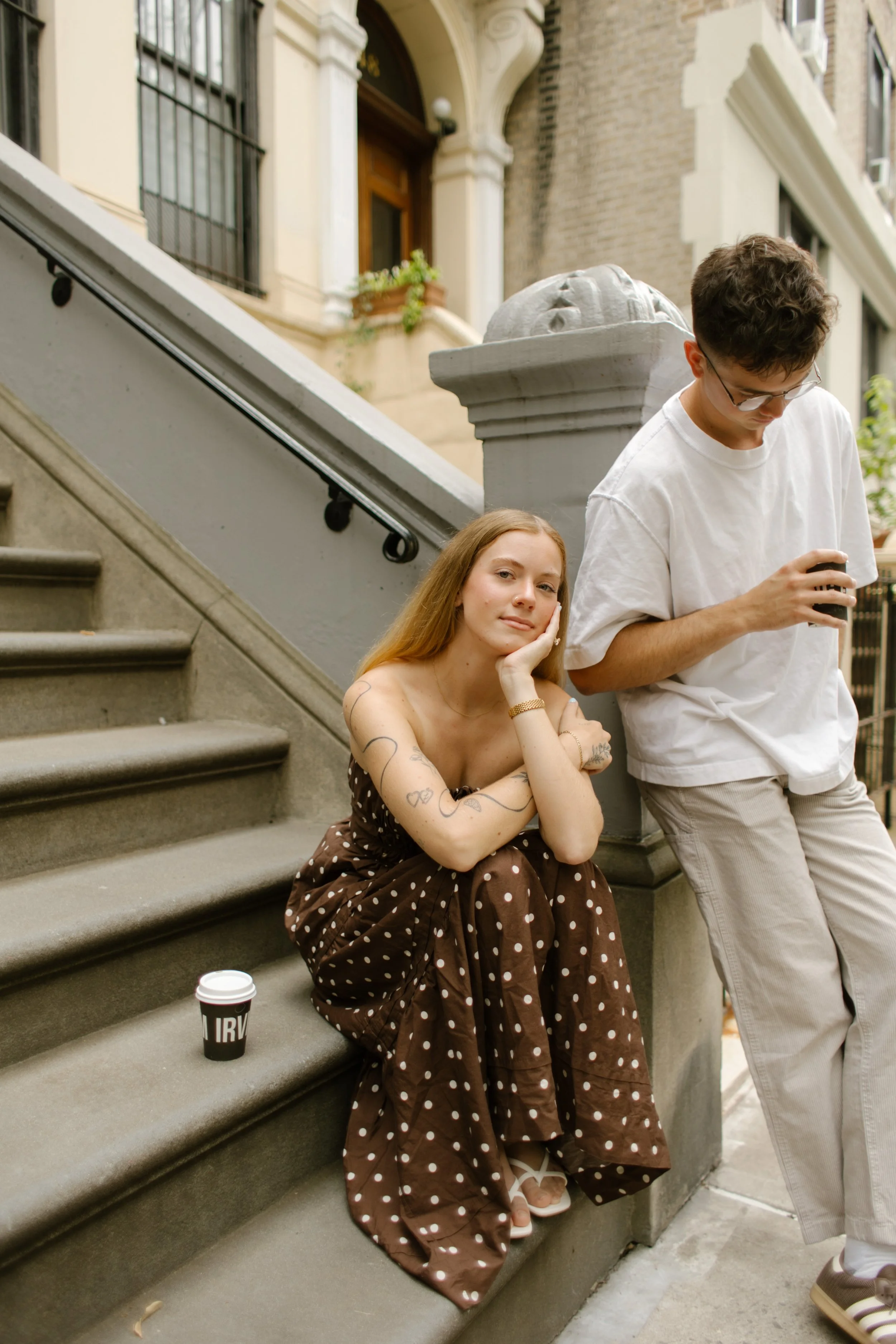 New York engagement photographer capturing a relaxed brownstone stoop portrait with coffee and candid moments.