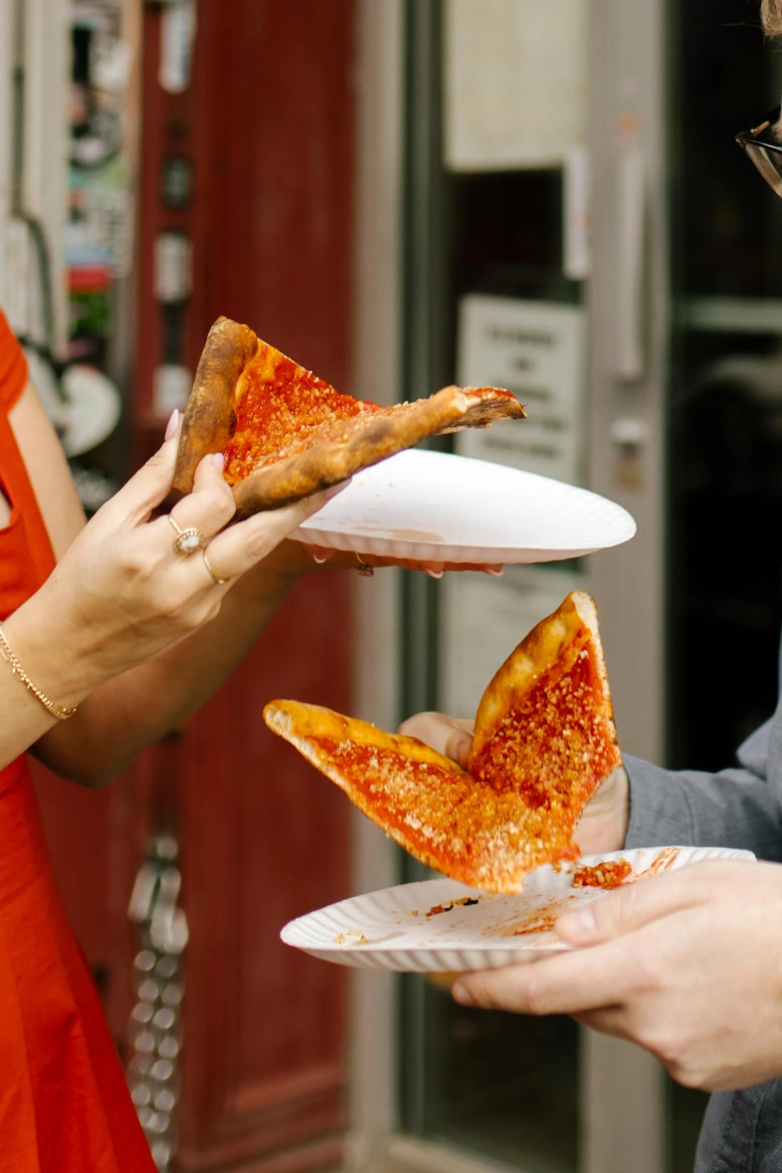 Couple sharing classic New York pizza during a playful city engagement session.