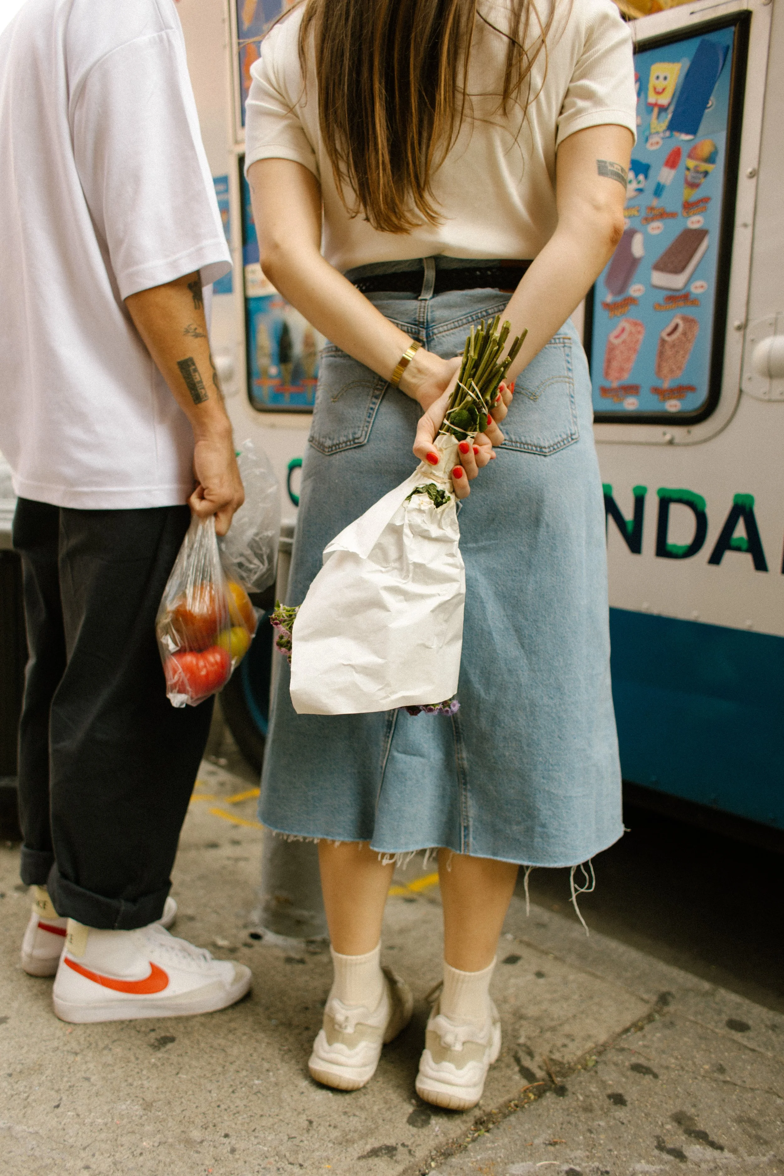Close-up of a couple holding flowers and fresh produce after shopping at a New York City street market.
