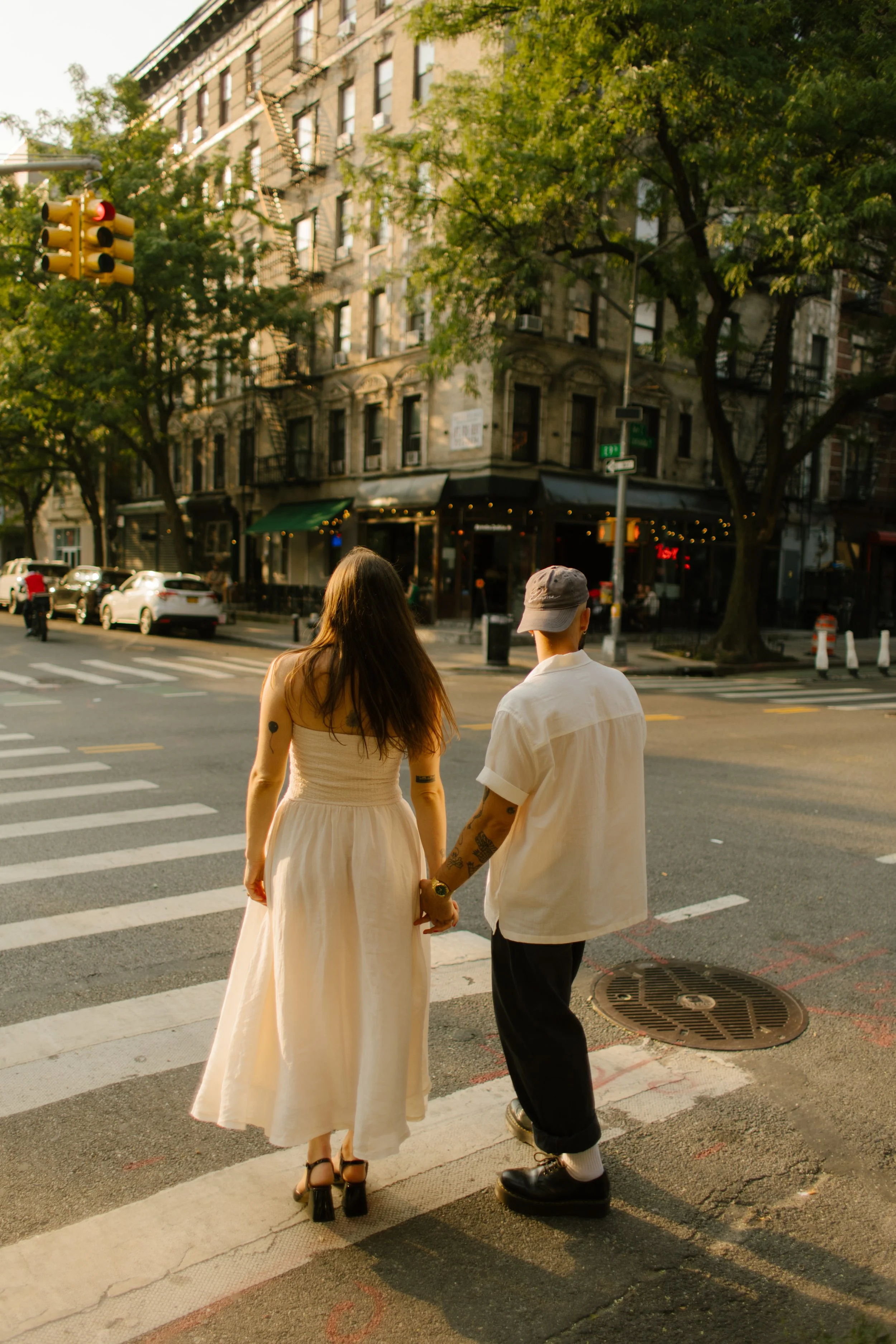 Couple holding hands at a quiet Manhattan intersection during a golden hour engagement session.