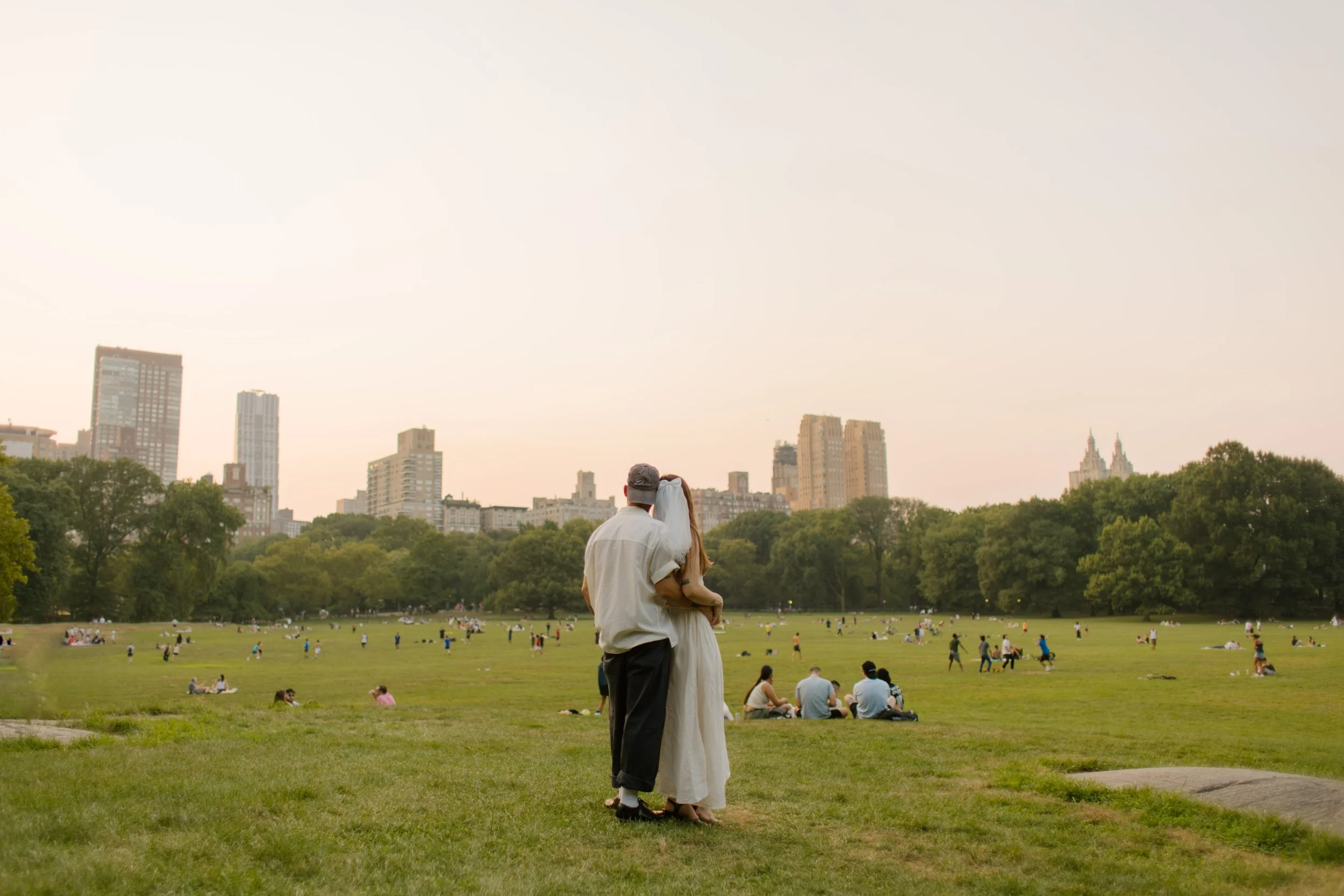 Couple embracing in Sheep Meadow during a relaxed Central Park engagement session at golden hour.
