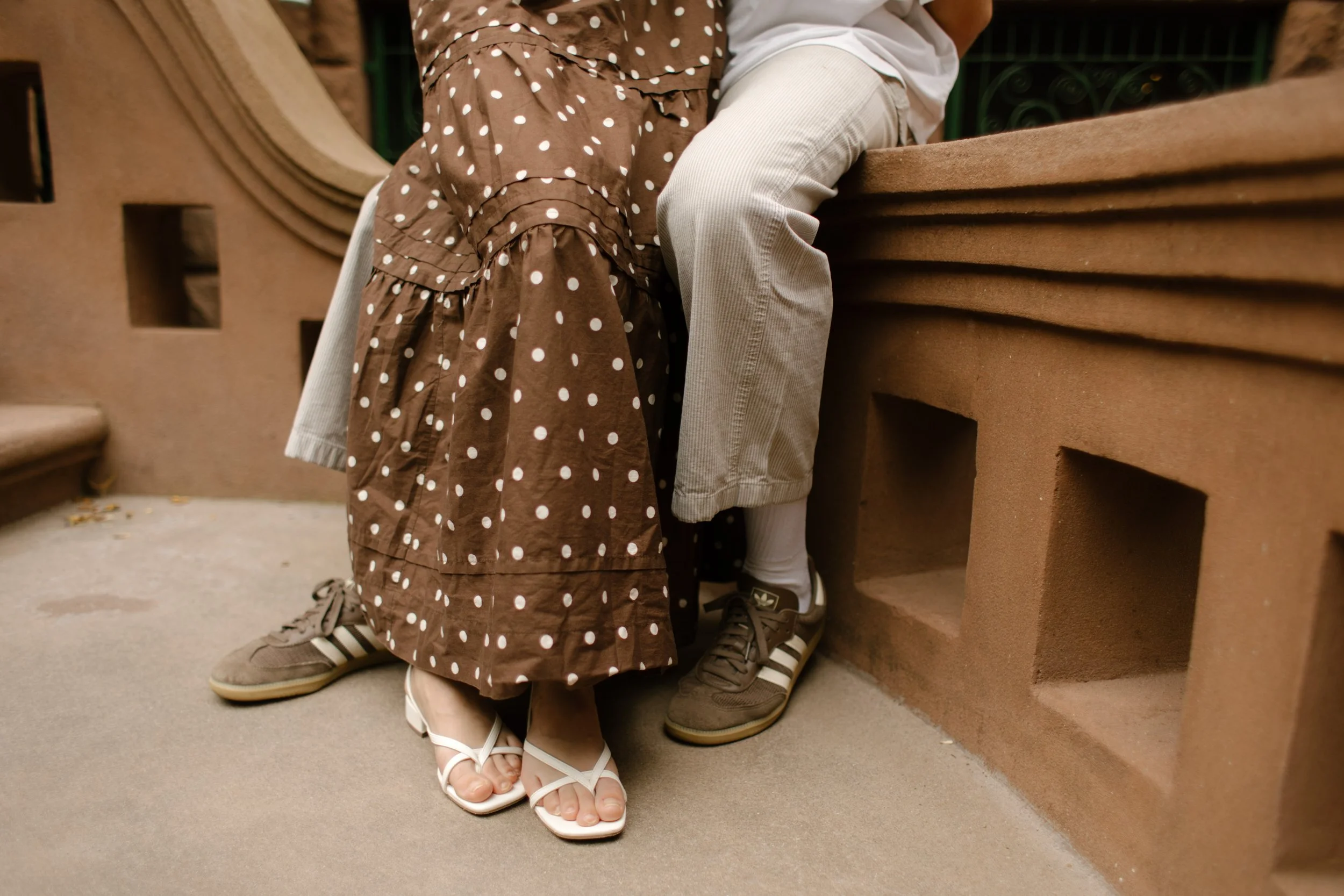 Close-up of a couple sitting together on a Brooklyn brownstone stoop during a casual engagement shoot.