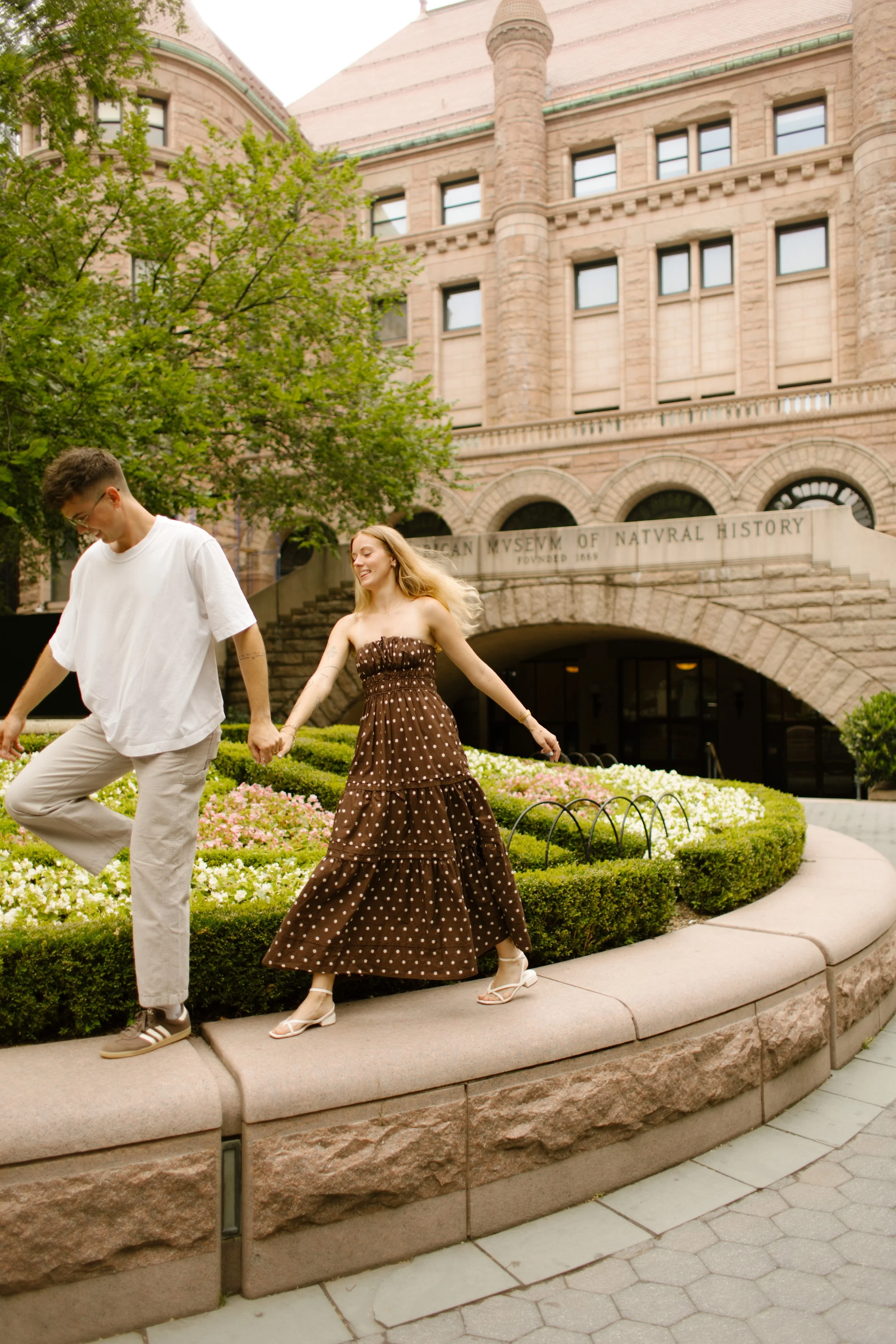 New York engagement photographer documenting a couple walking outside the American Museum of Natural History.