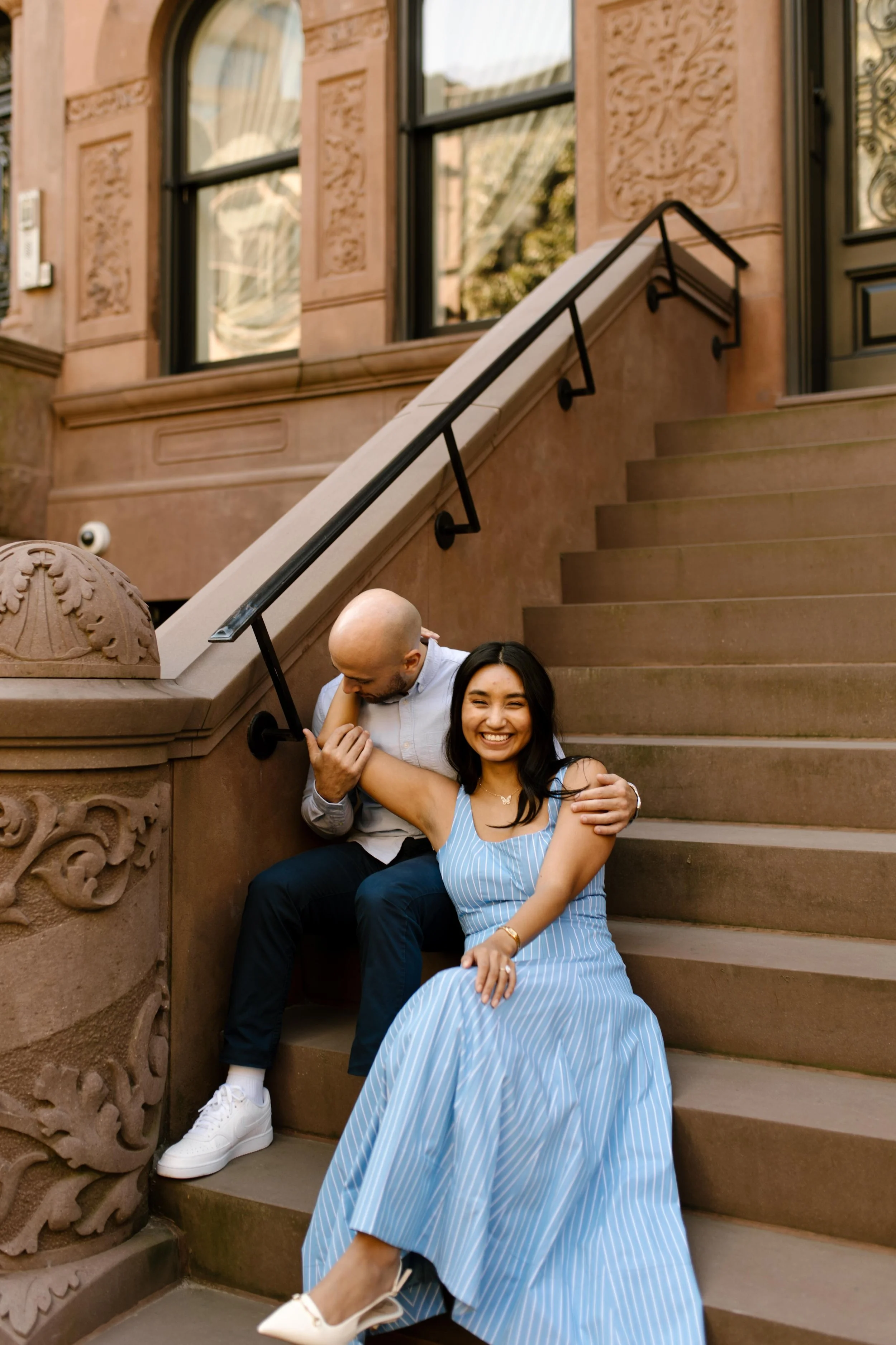 Couple sitting together on a Brooklyn brownstone stoop during a warm and candid engagement session.