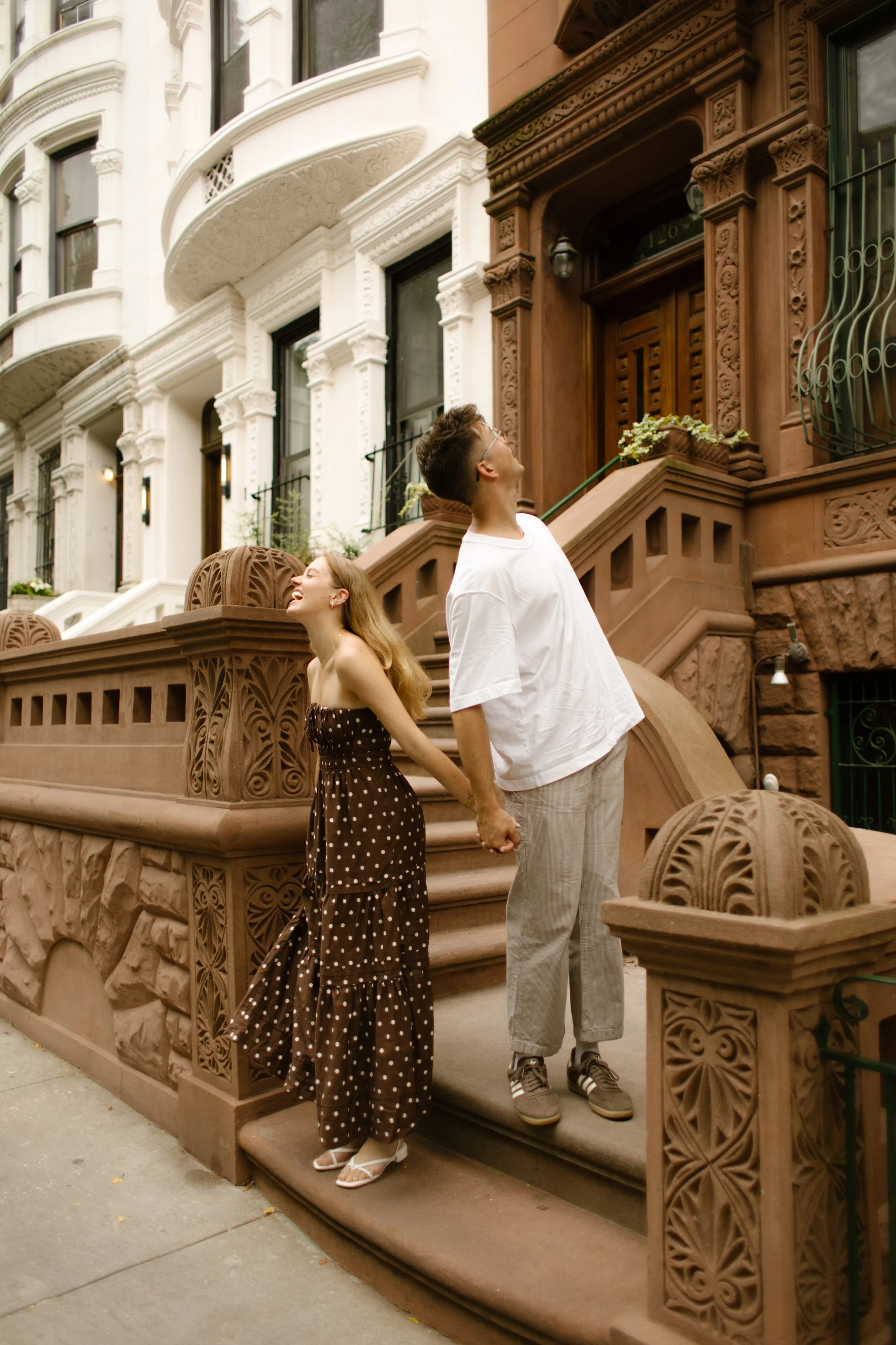 Couple holding hands on a Brooklyn brownstone stoop during a candid New York City engagement session.