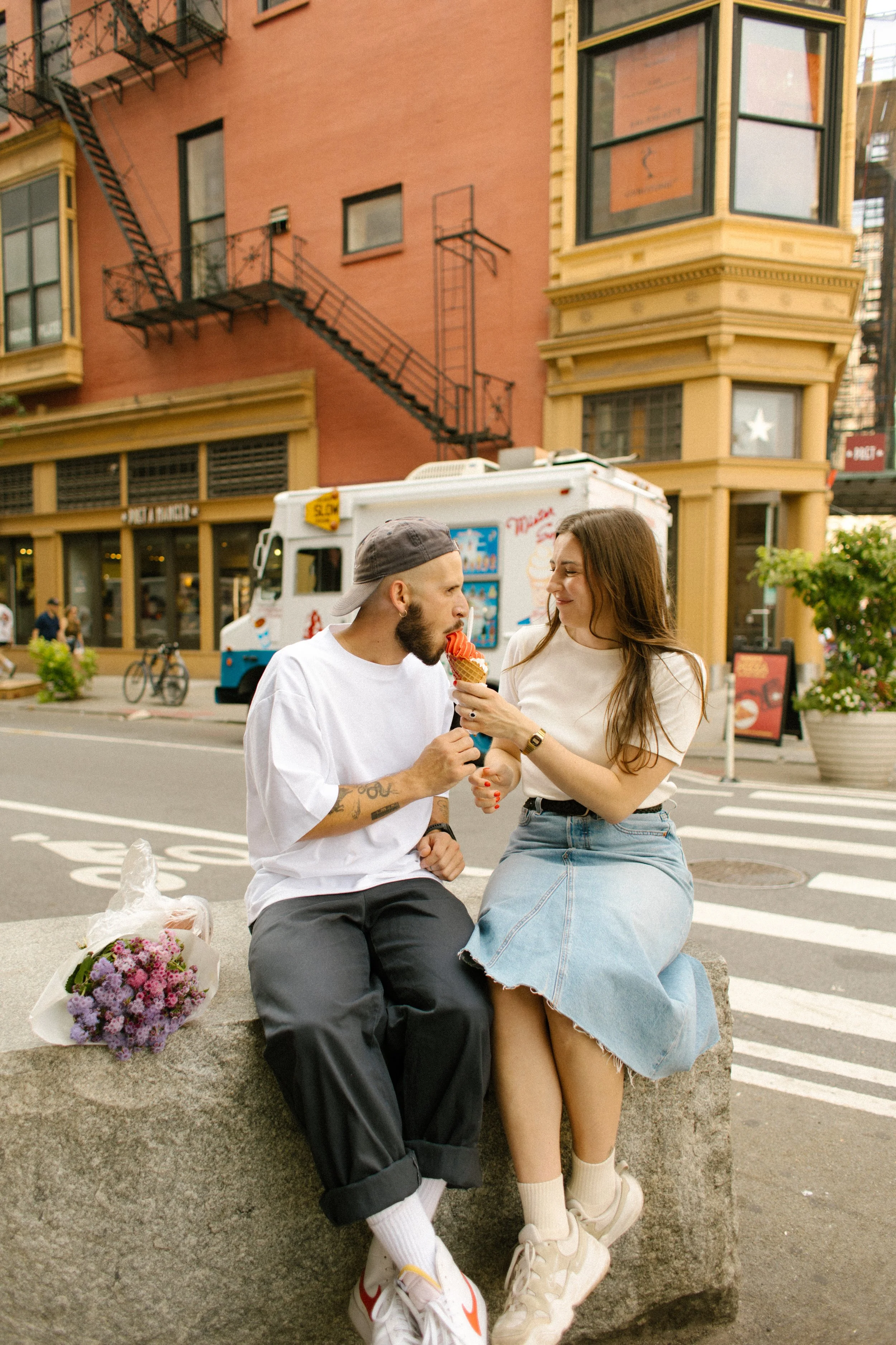Couple sharing ice cream together on a West Village street during a playful engagement shoot.
