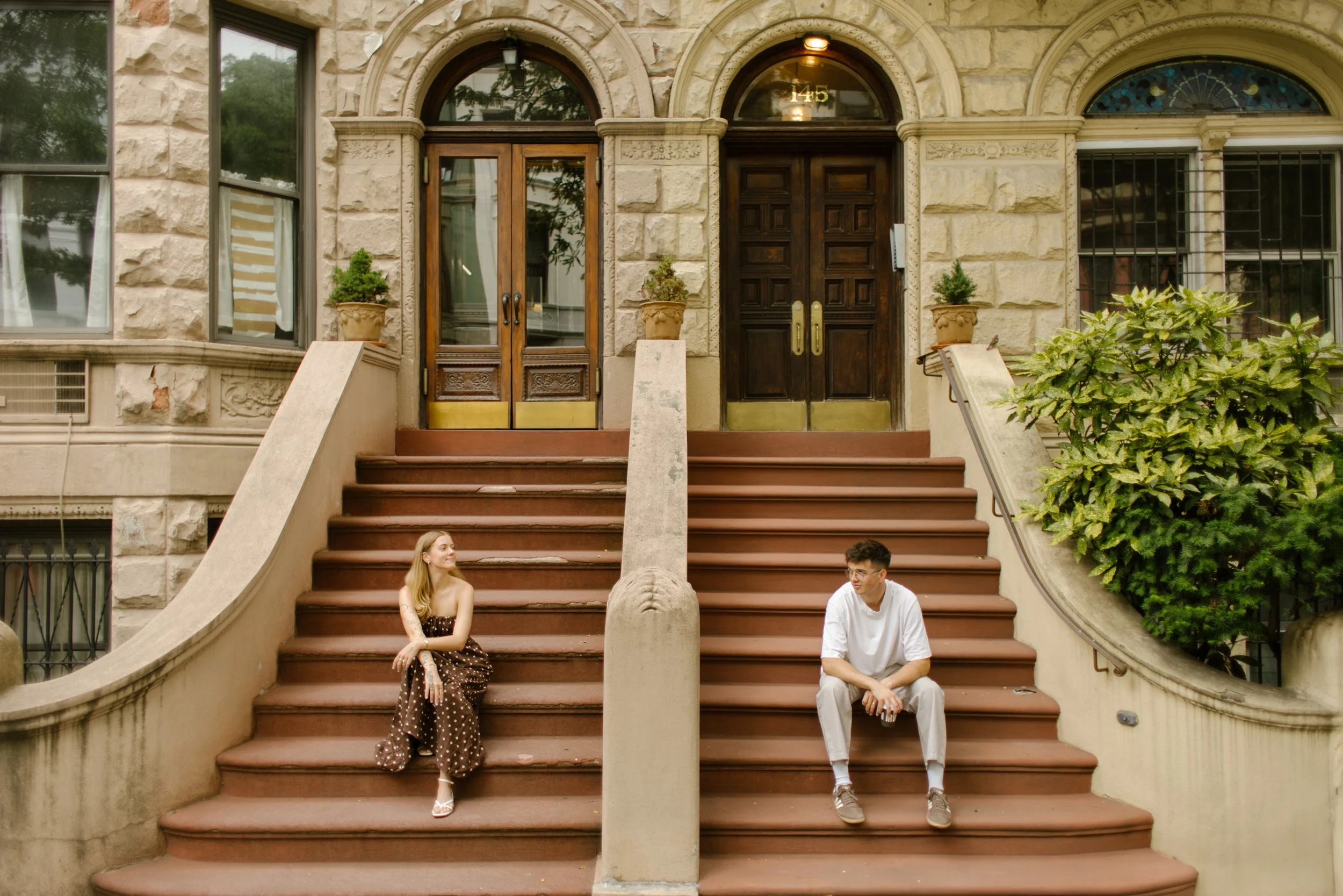 New York engagement photographer photographing a couple sitting apart on a Brooklyn brownstone stoop for an editorial-style portrait.