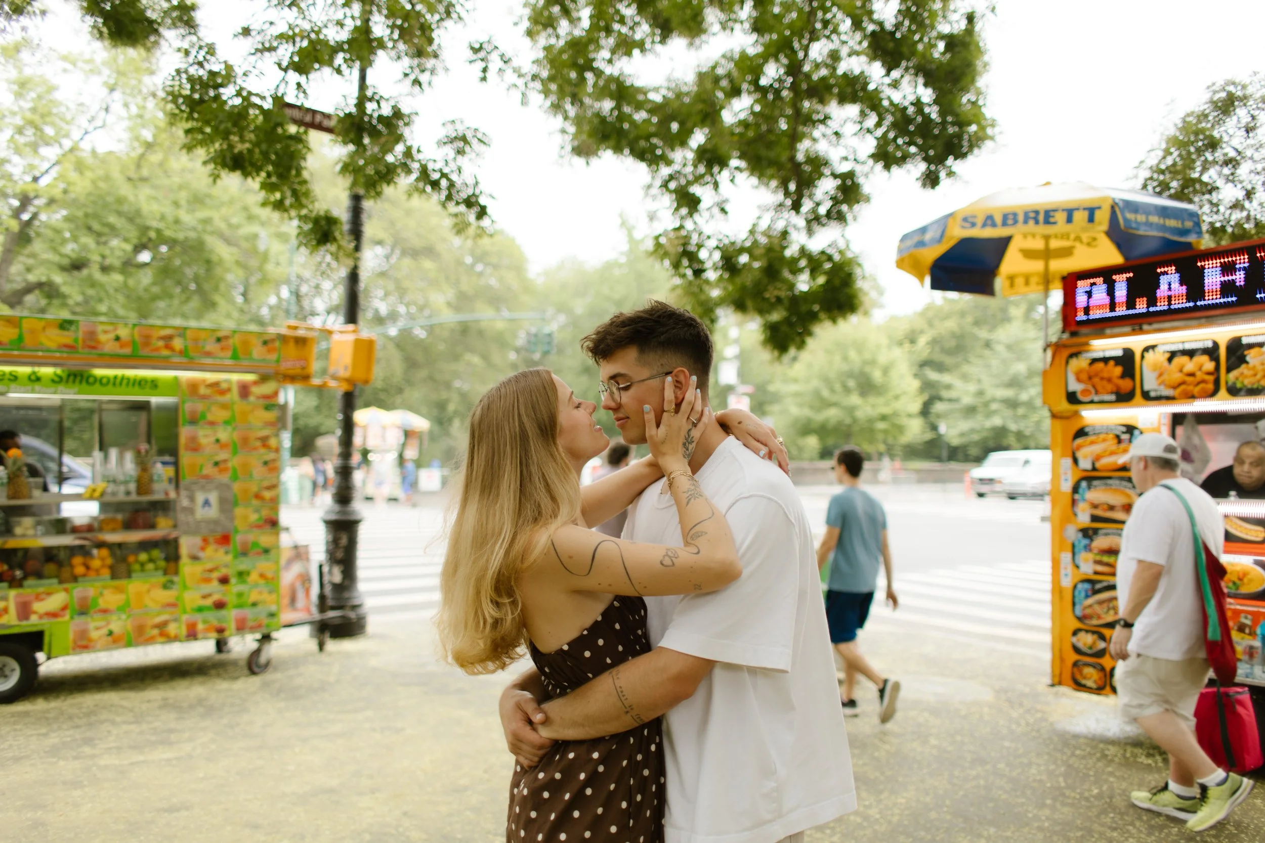 Romantic embrace beside Central Park food carts during a relaxed autumn engagement session.