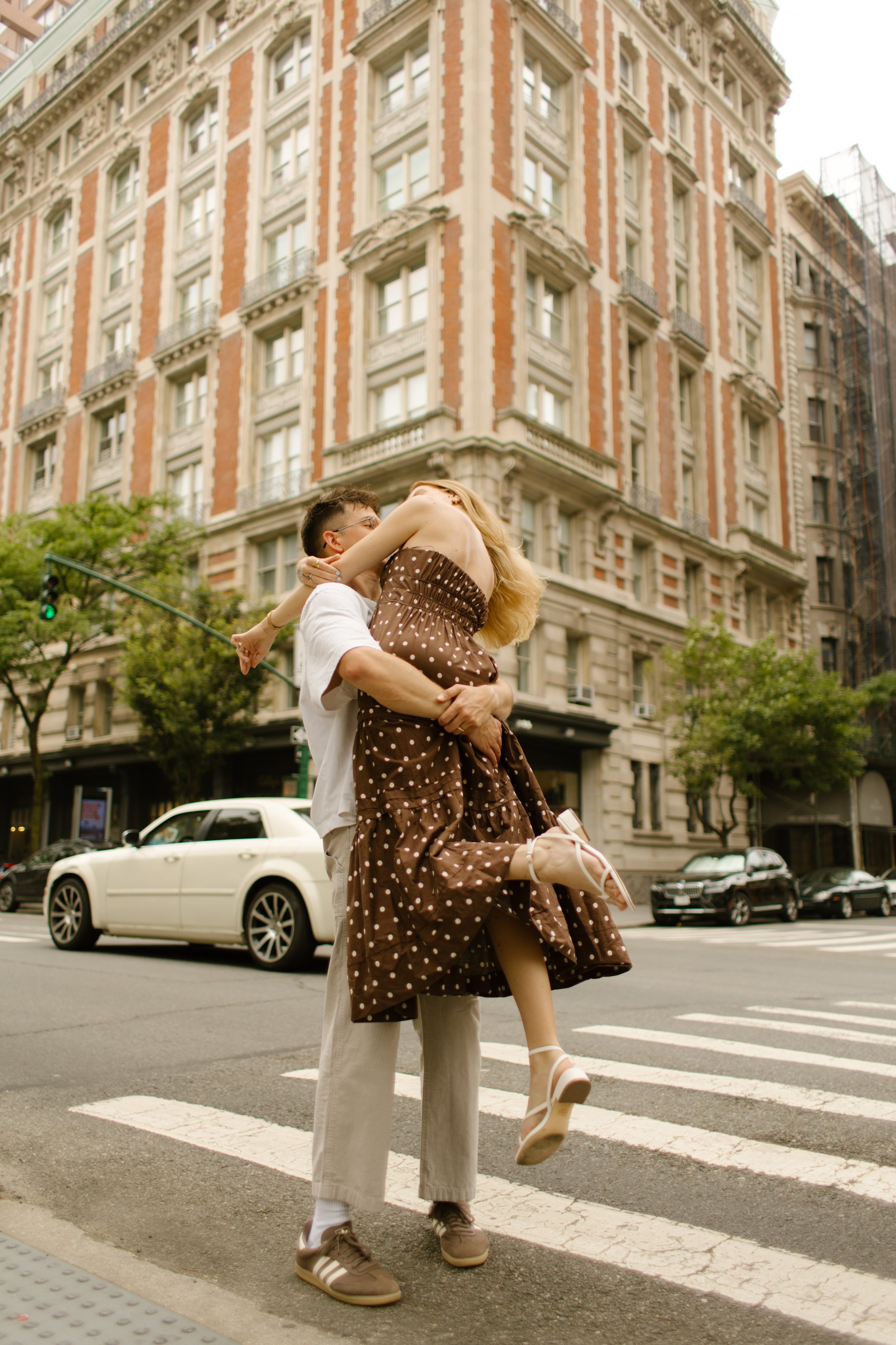 Couple embracing in the middle of a Manhattan crosswalk during a playful city engagement shoot.
