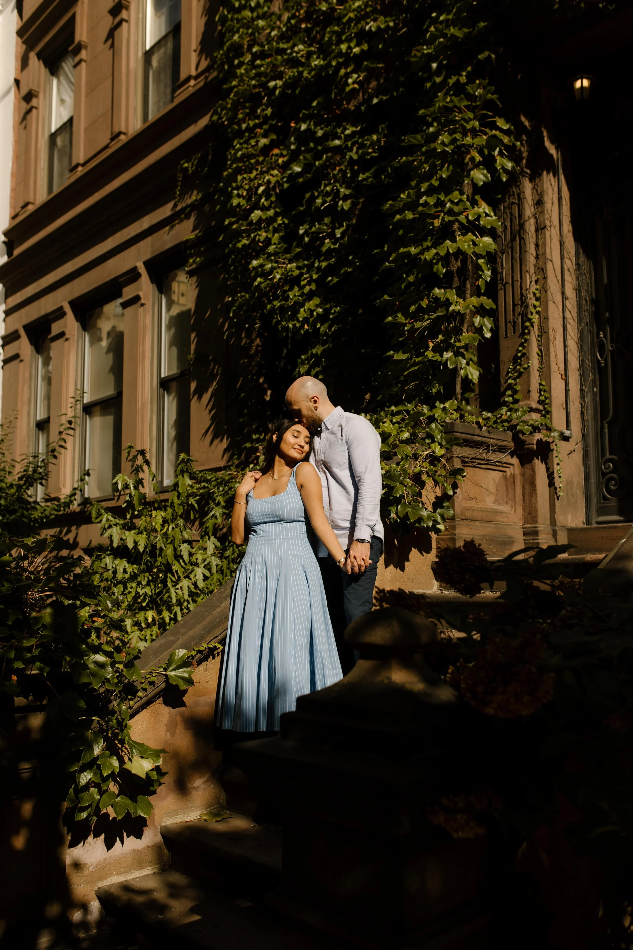 New York engagement photographer photographing a couple embracing on ivy-covered Brooklyn brownstone steps.