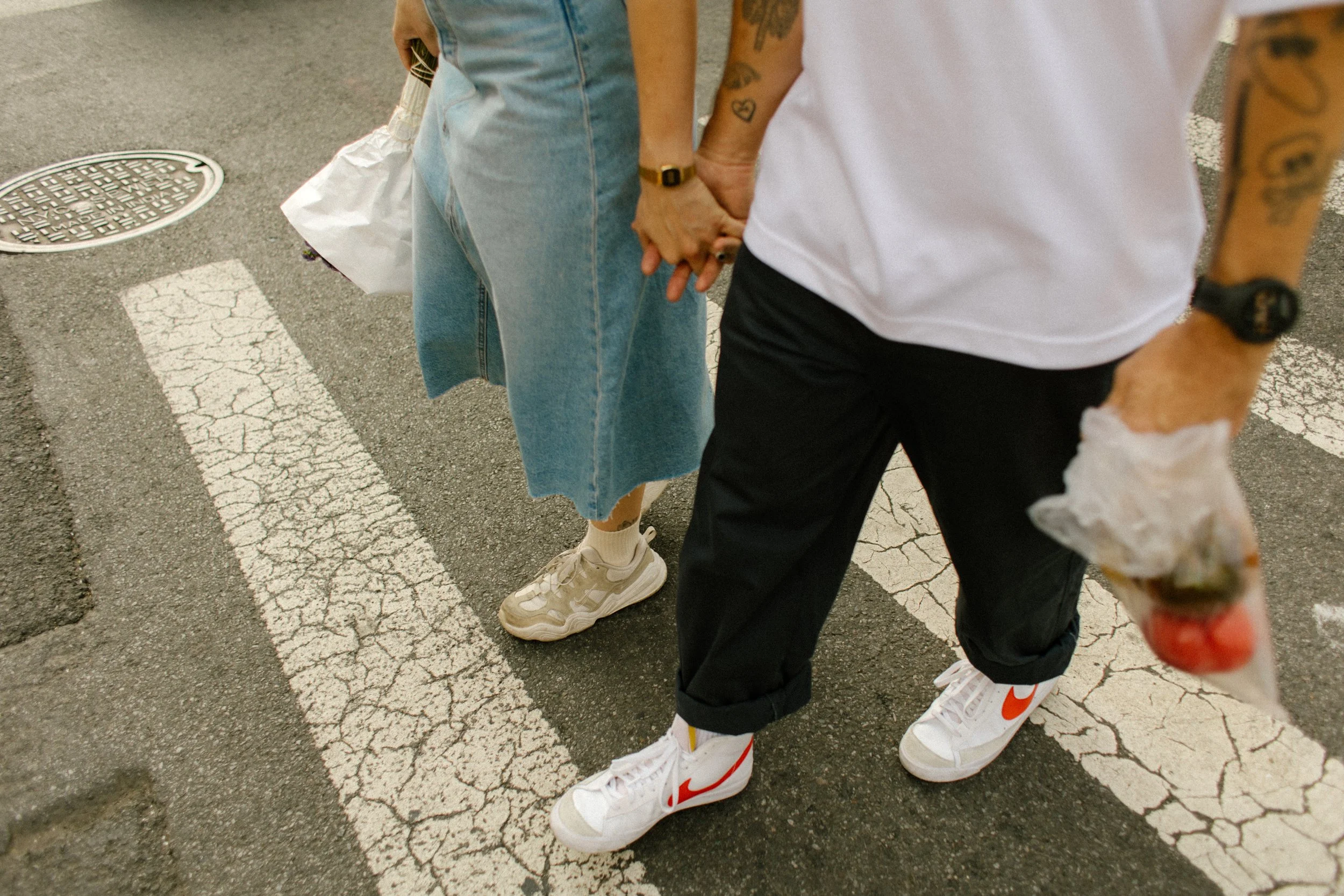 New York engagement photographer capturing a couple holding hands while crossing a Manhattan street after the farmers market.
