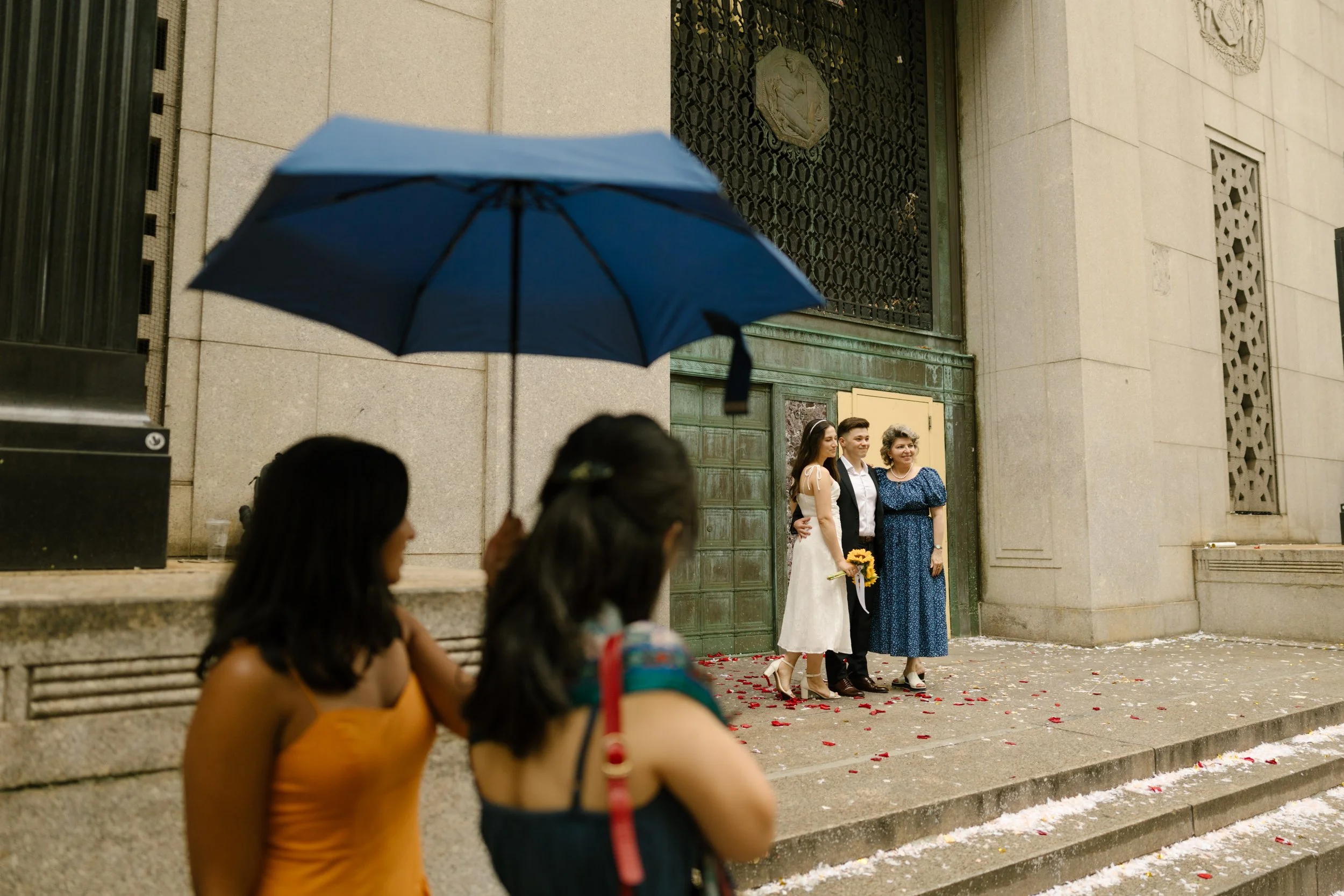 Guests holding umbrella outside rainy New York Wedding ceremony exit in Manhattan