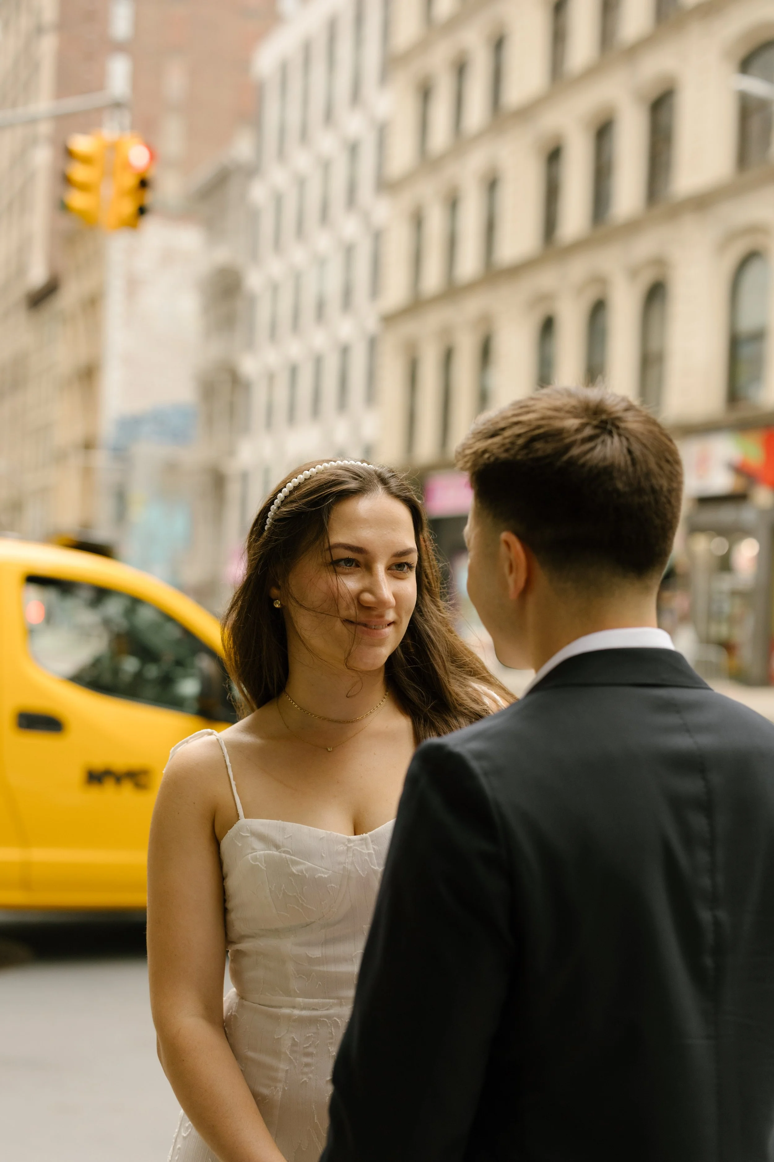 Bride smiling at groom beside yellow NYC taxi during downtown New York Wedding portraits