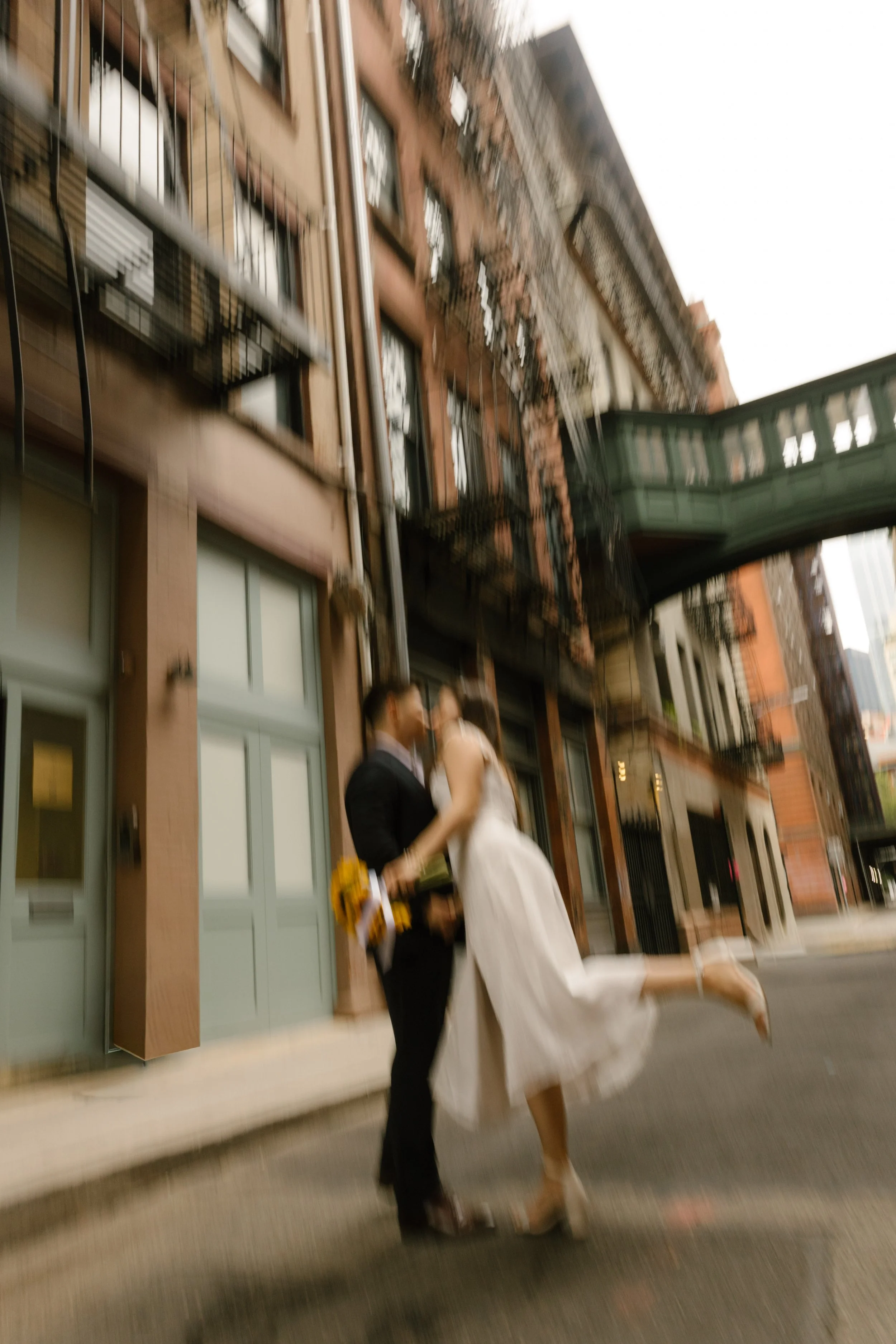 Motion blur portrait of bride and groom kissing on quiet SoHo street in Manhattan
