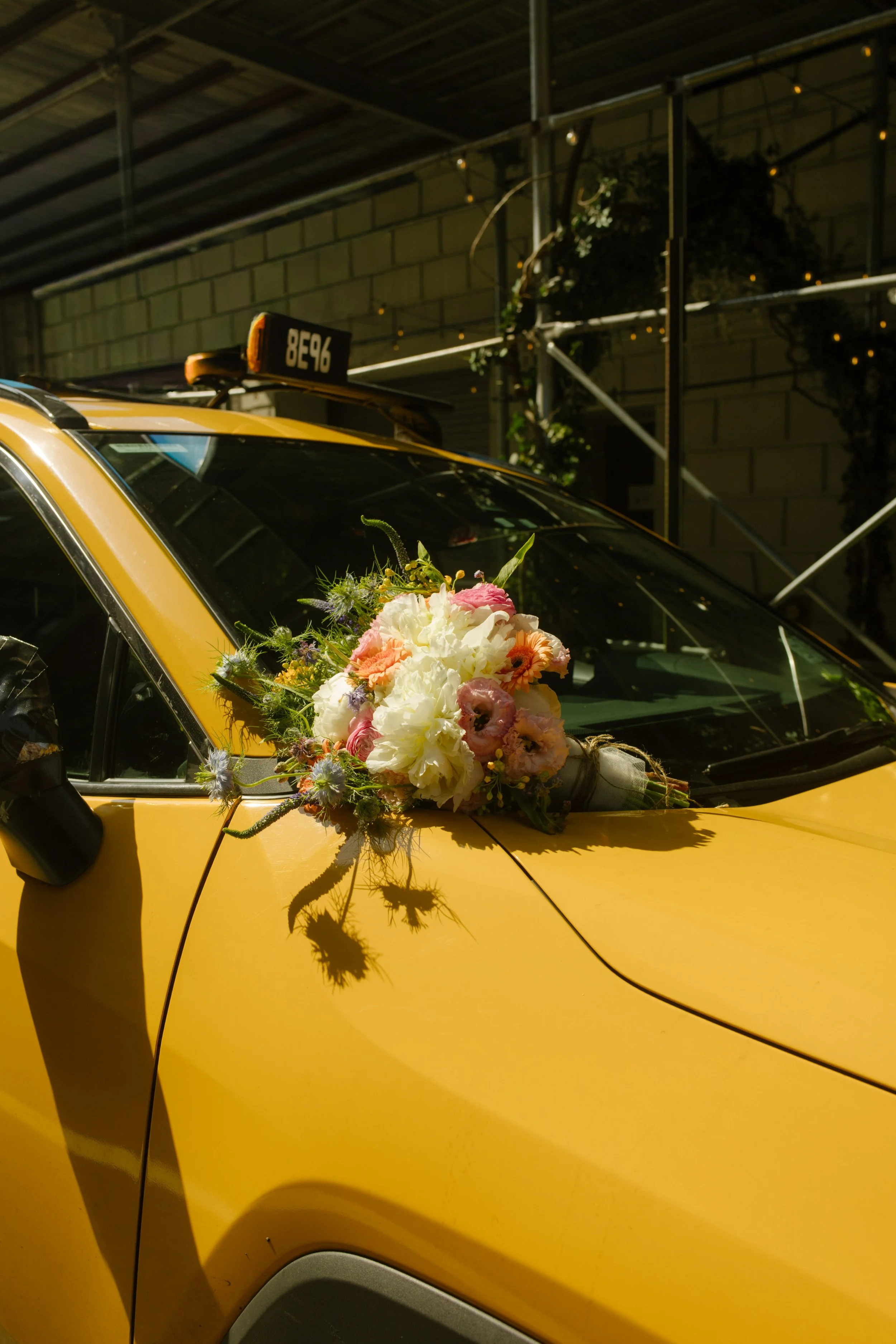 Bridal bouquet resting on yellow NYC taxi outside Manhattan wedding venue