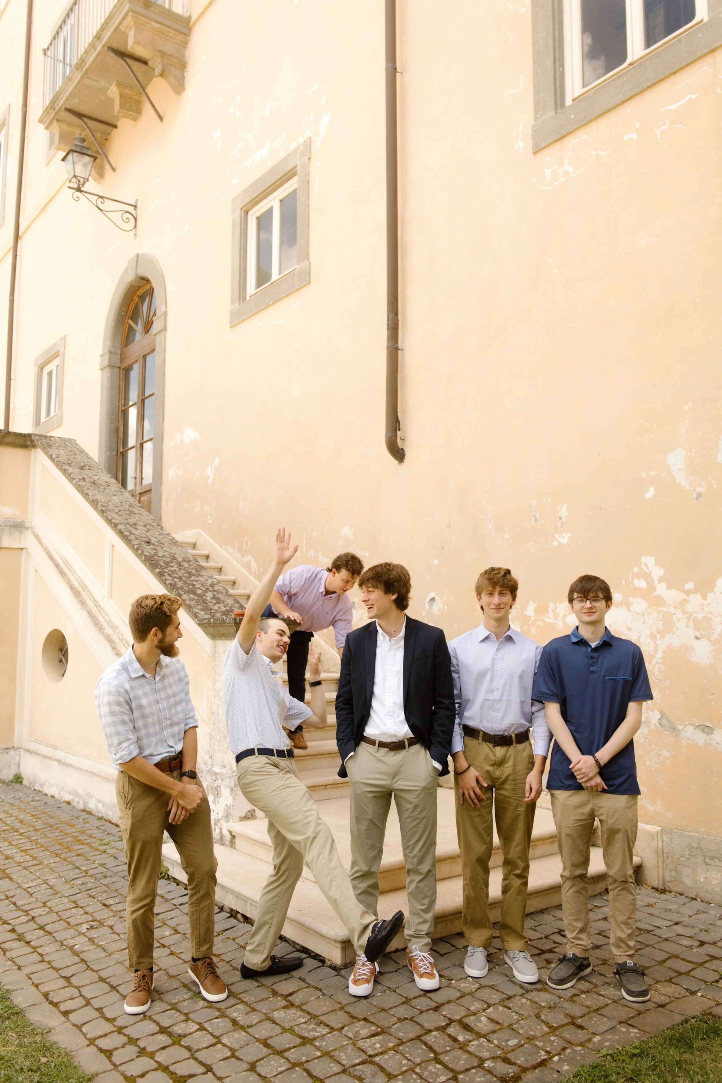Groom and friends laughing outside a historic villa during a destination wedding in Italy celebration