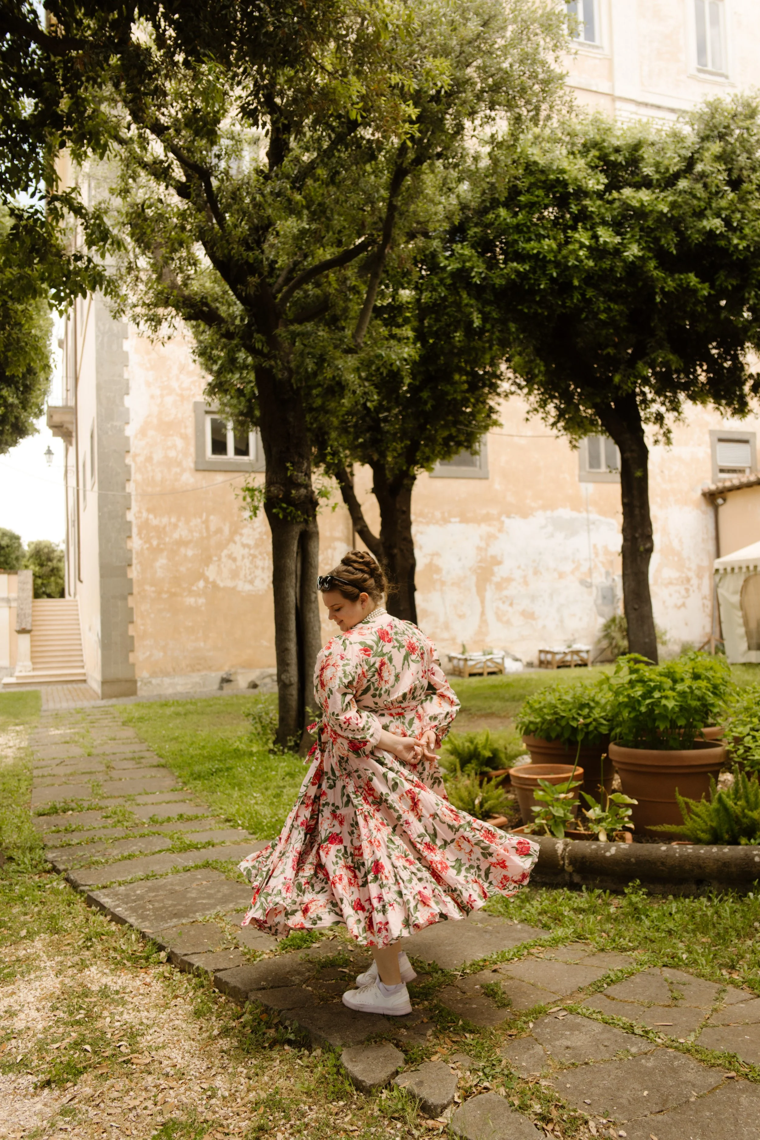 Woman twirling in a floral dress outside a historic villa during a destination wedding in Italy wedding weekend