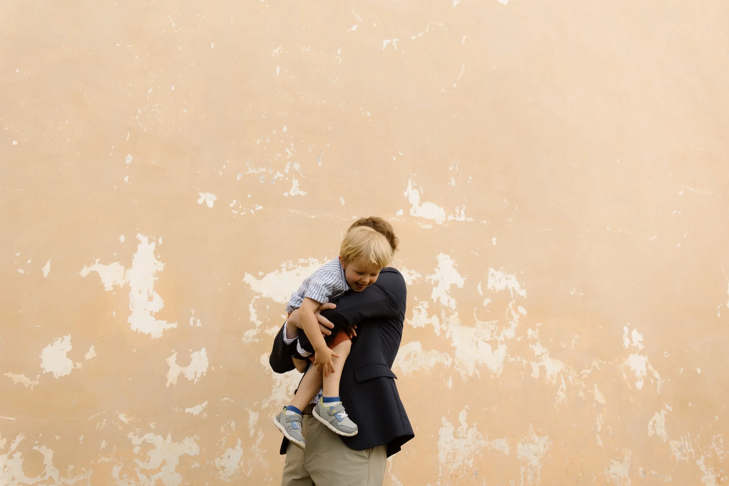 Groom holding a child in front of a historic Italian villa during a destination wedding in Italy
