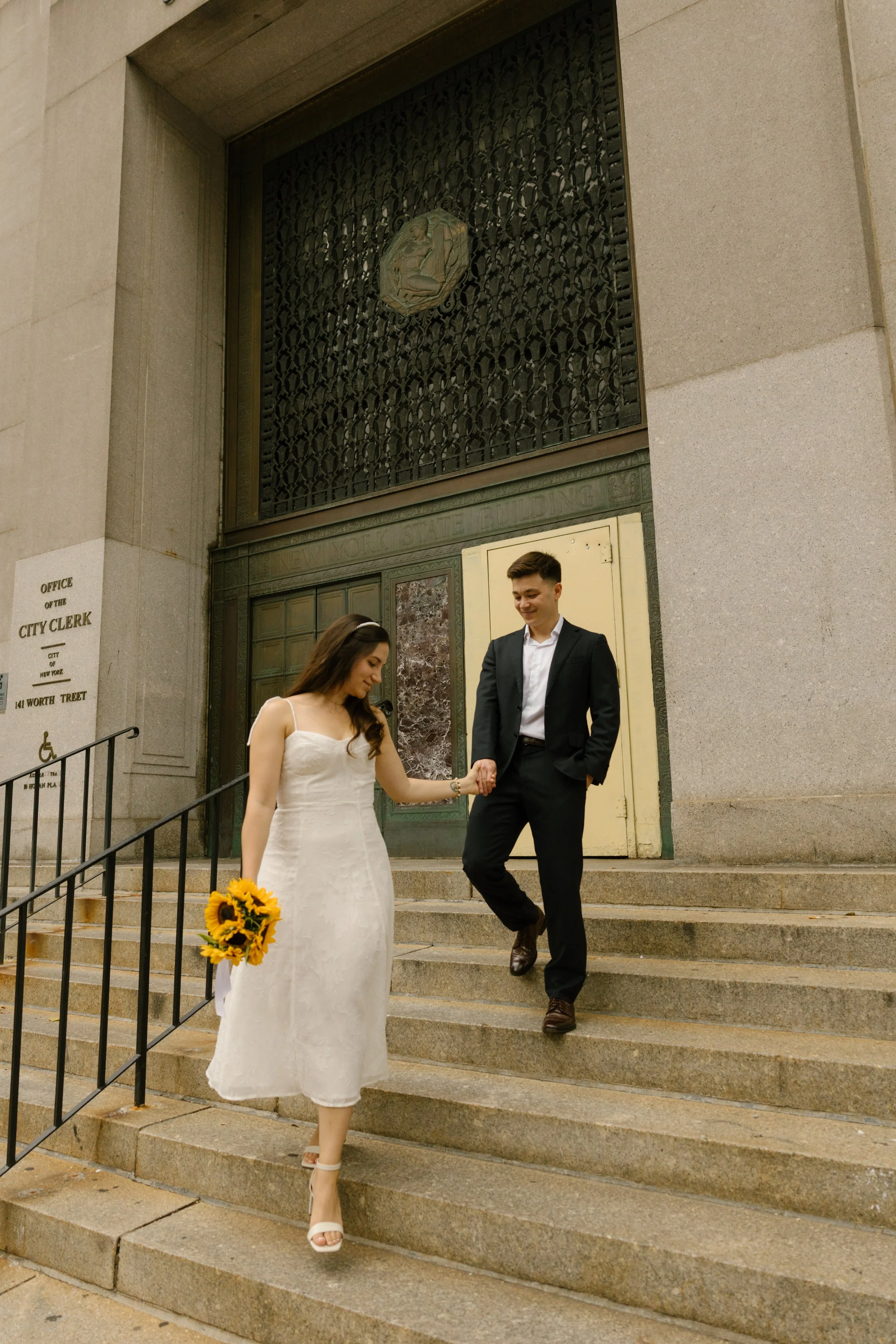 Bride leading groom down courthouse steps after their New York courthouse wedding ceremony