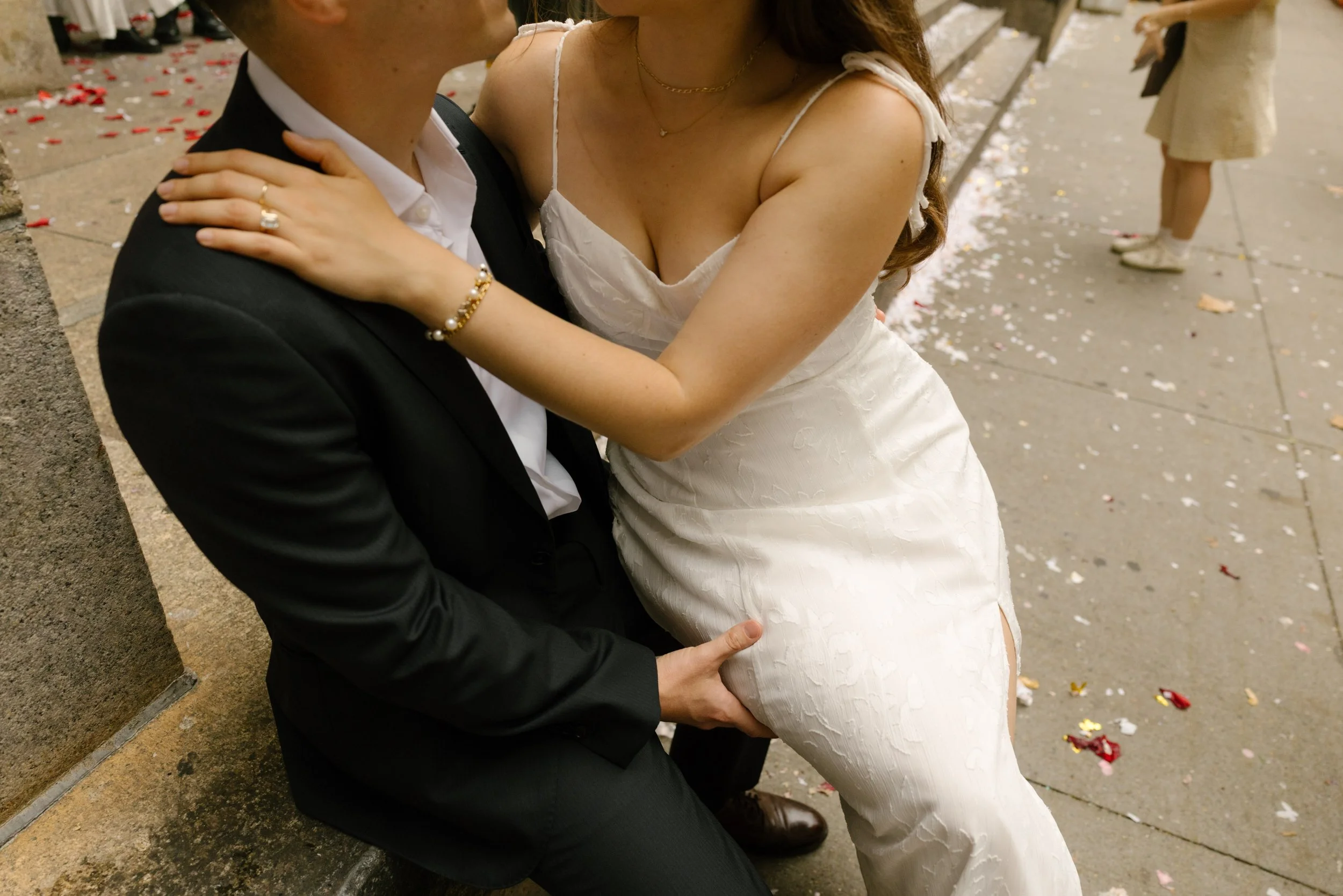 Close-up of bride embracing groom while sitting on courthouse steps after elopement