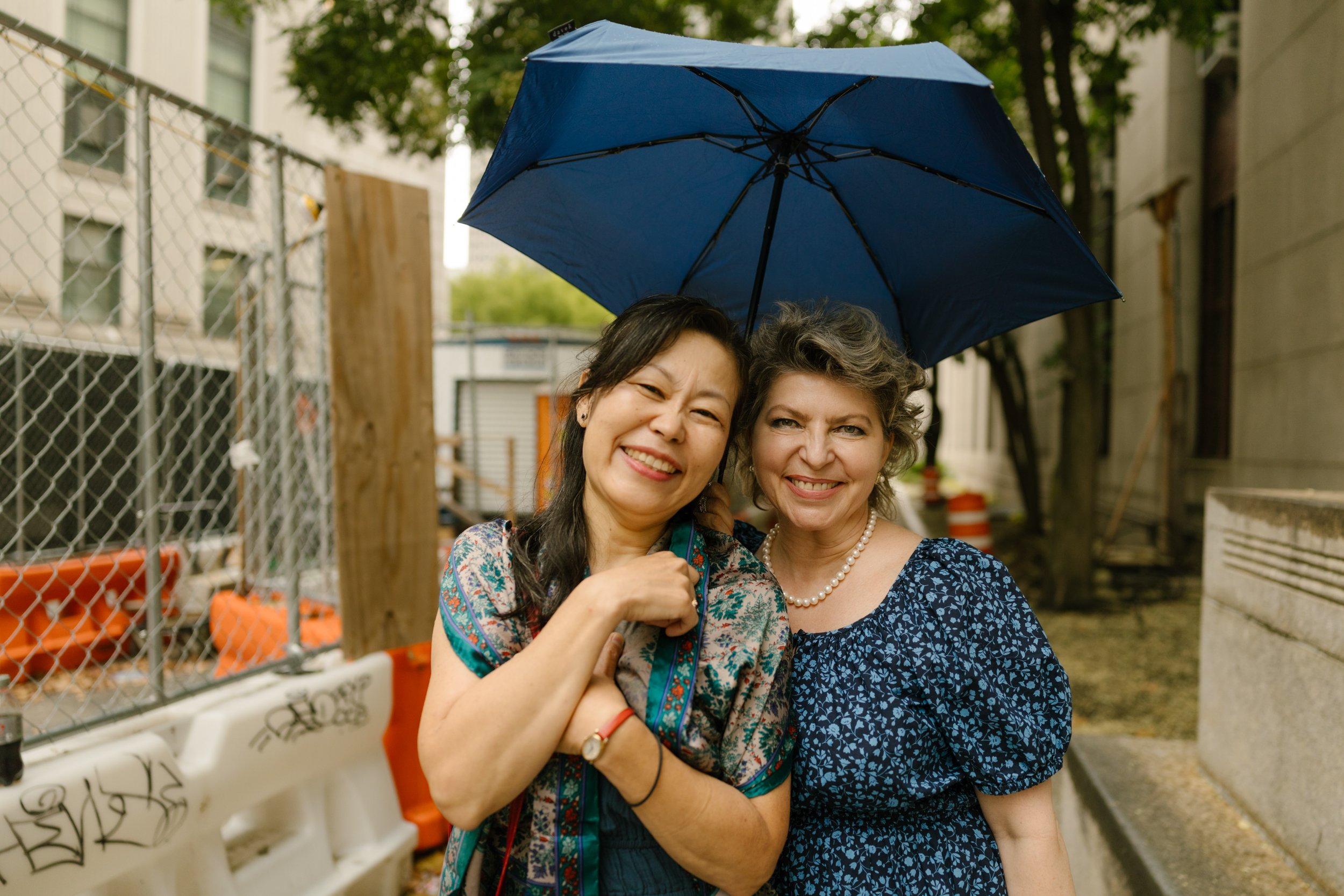 Family members holding umbrellas together outside the courthouse on a cloudy NYC wedding day
