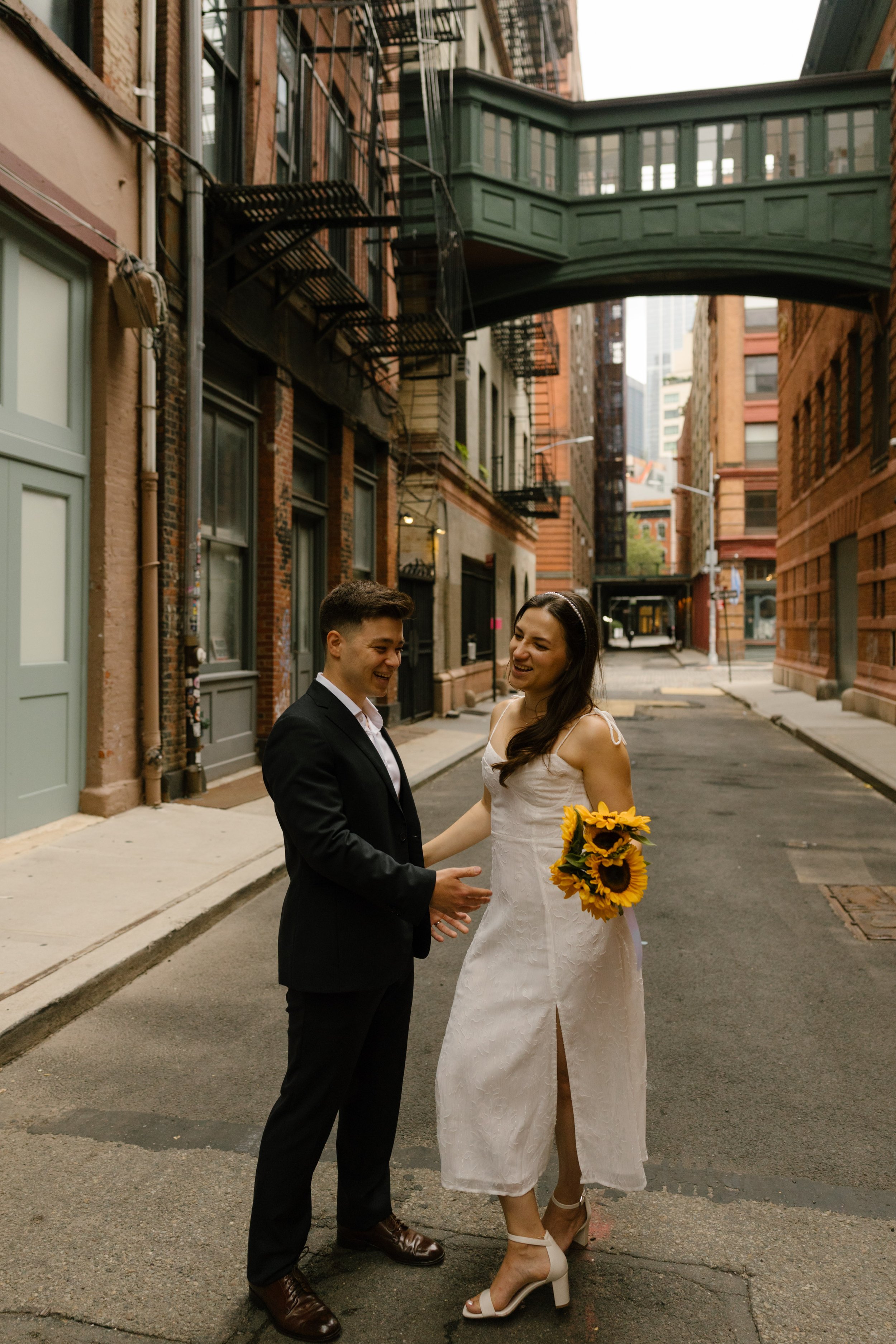 Couple laughing together beneath Staple Street Skybridge after their NYC courthouse wedding
