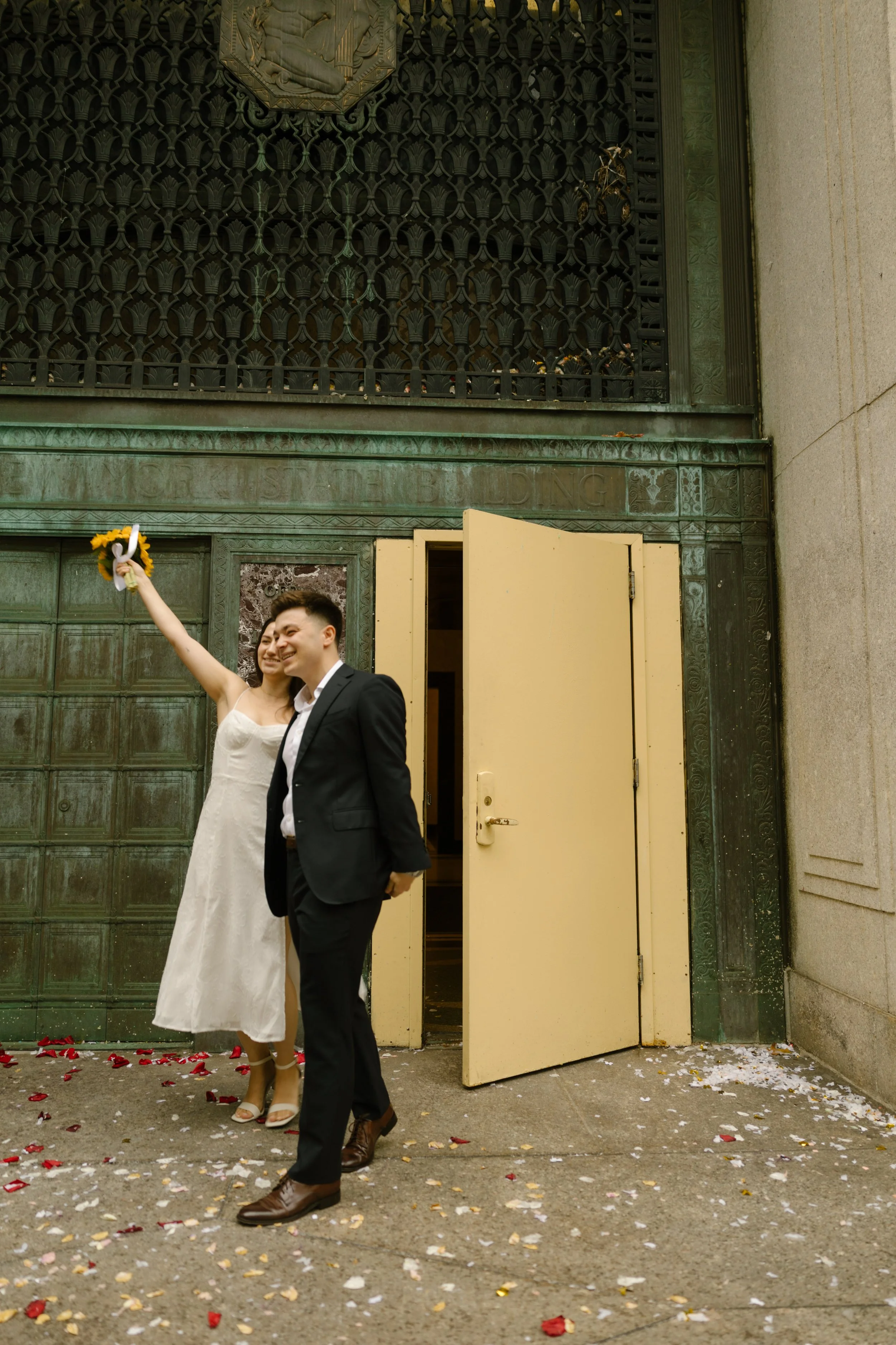 Couple celebrating outside the iconic yellow doors after their New York courthouse wedding ceremony
