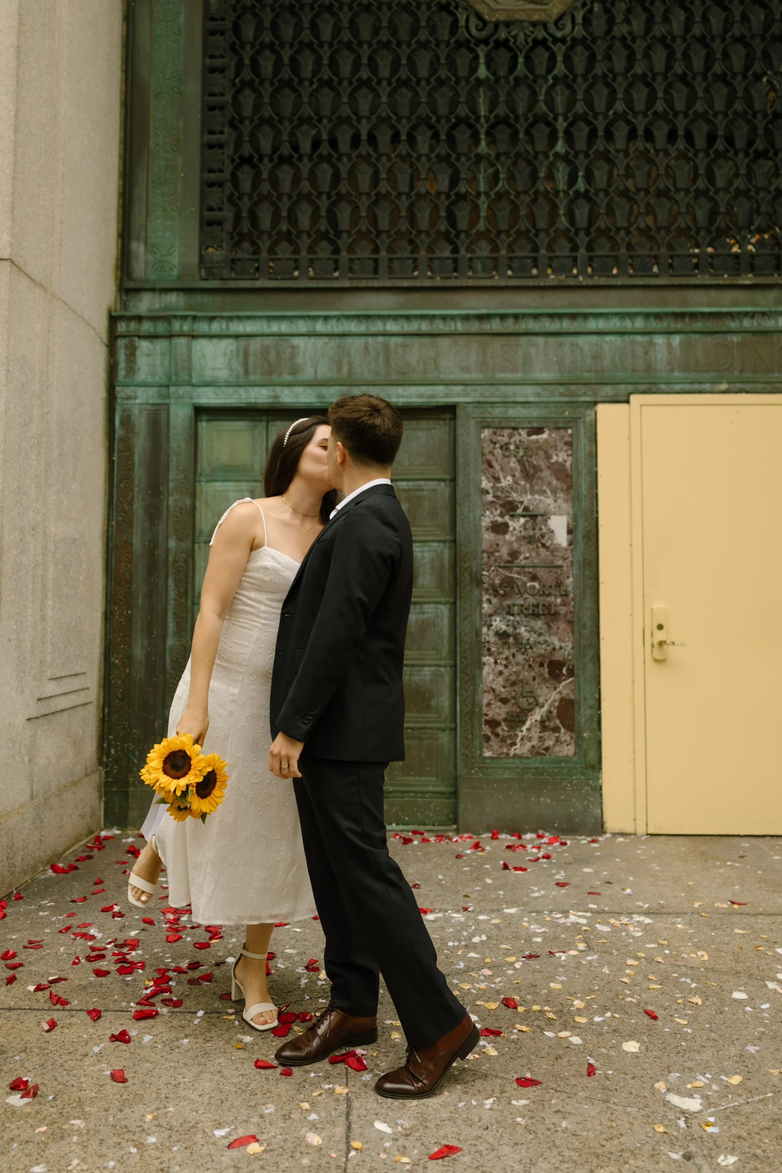 Couple kissing outside the iconic yellow doors during a New York courthouse wedding at the NYC City Clerk’s Office