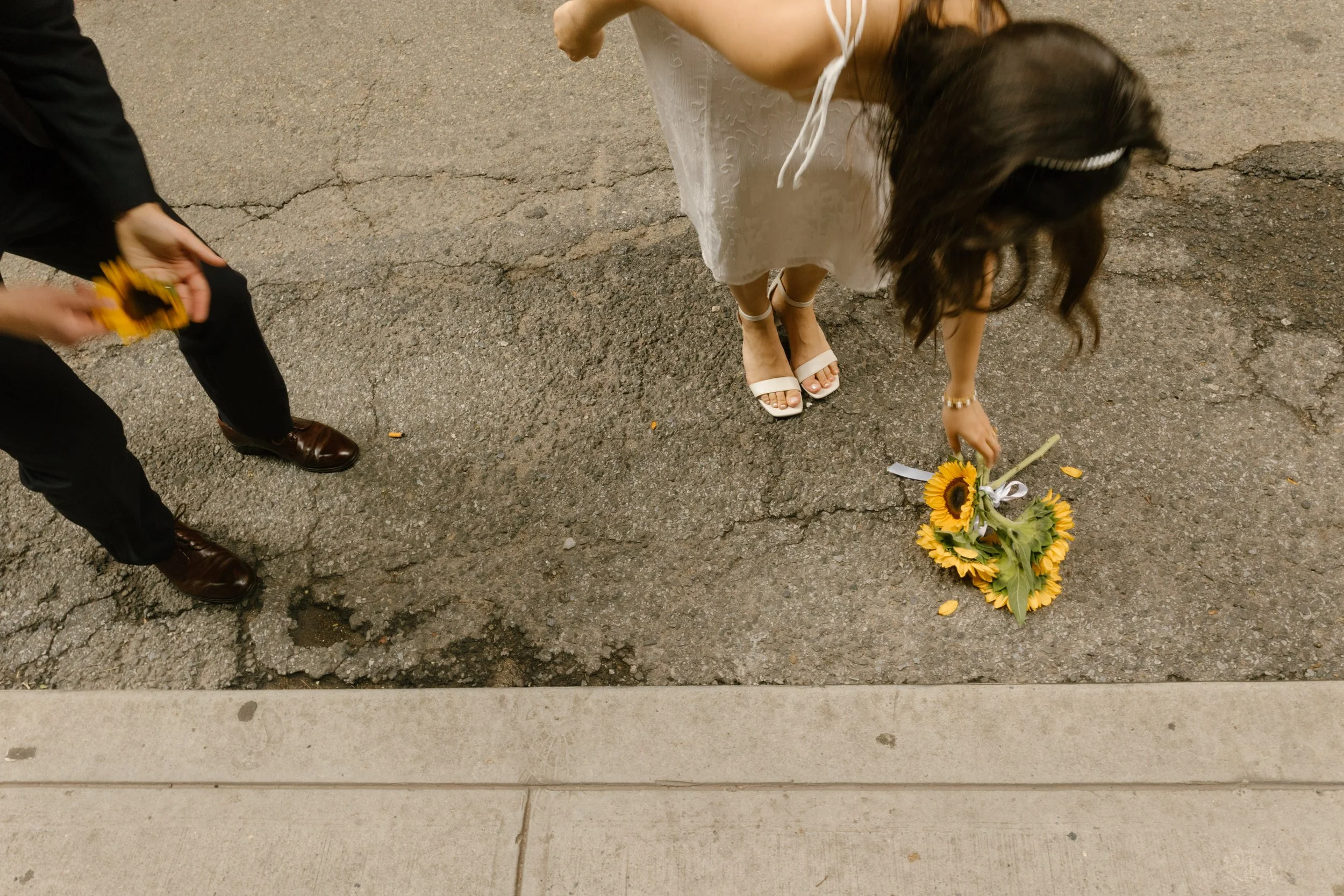 Bride picking up a sunflower bouquet during a candid New York courthouse wedding moment on NYC streets