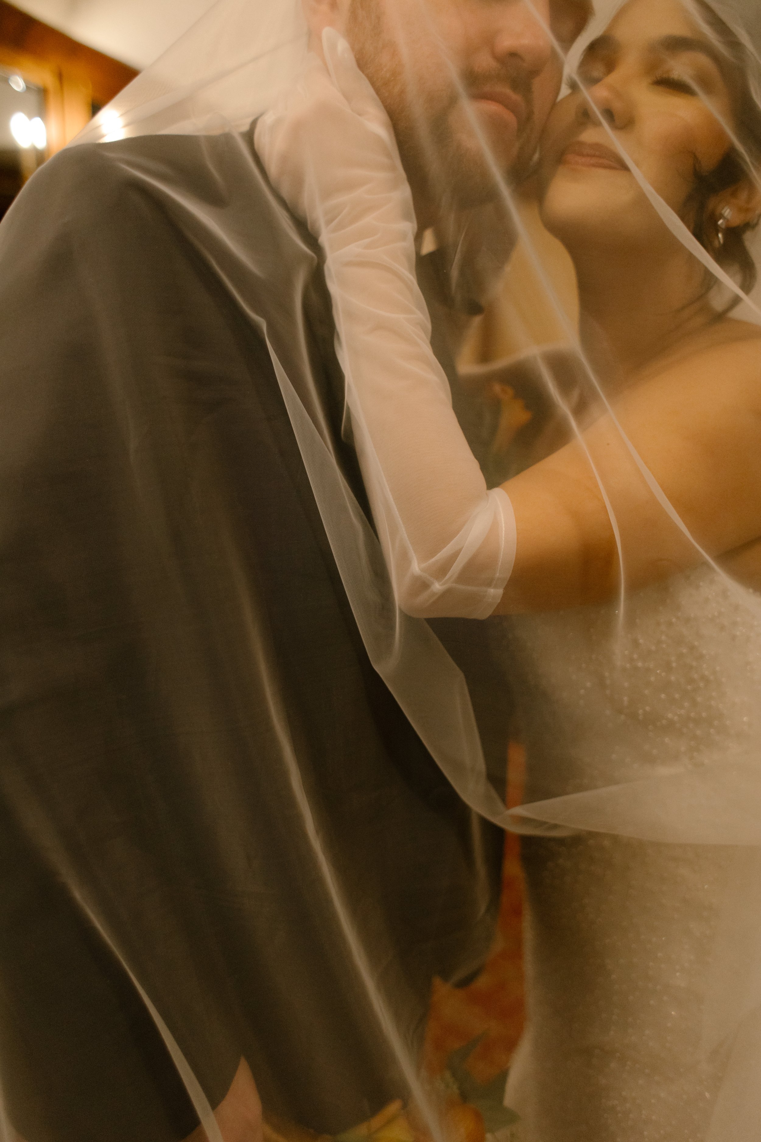 Romantic portrait of newlyweds embracing beneath a veil during their wedding in New York reception