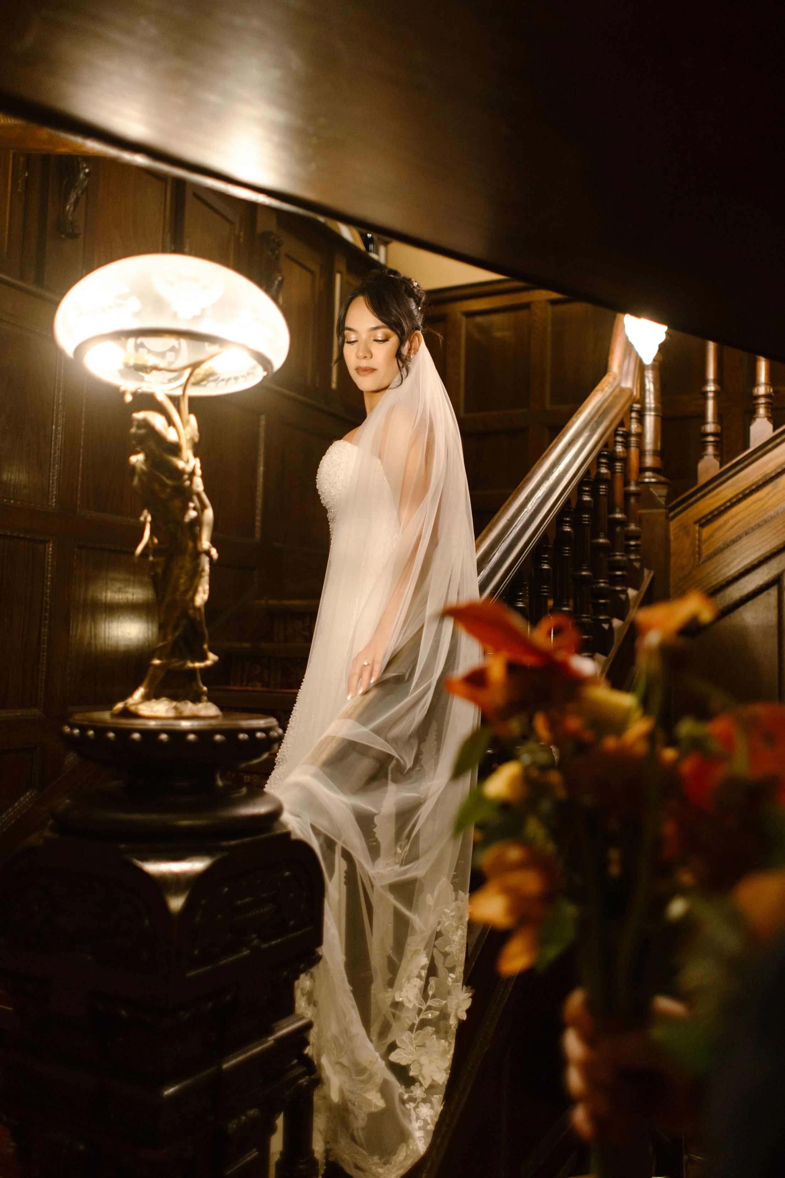 Bride standing on a grand staircase inside a historic mansion venue before the ceremony