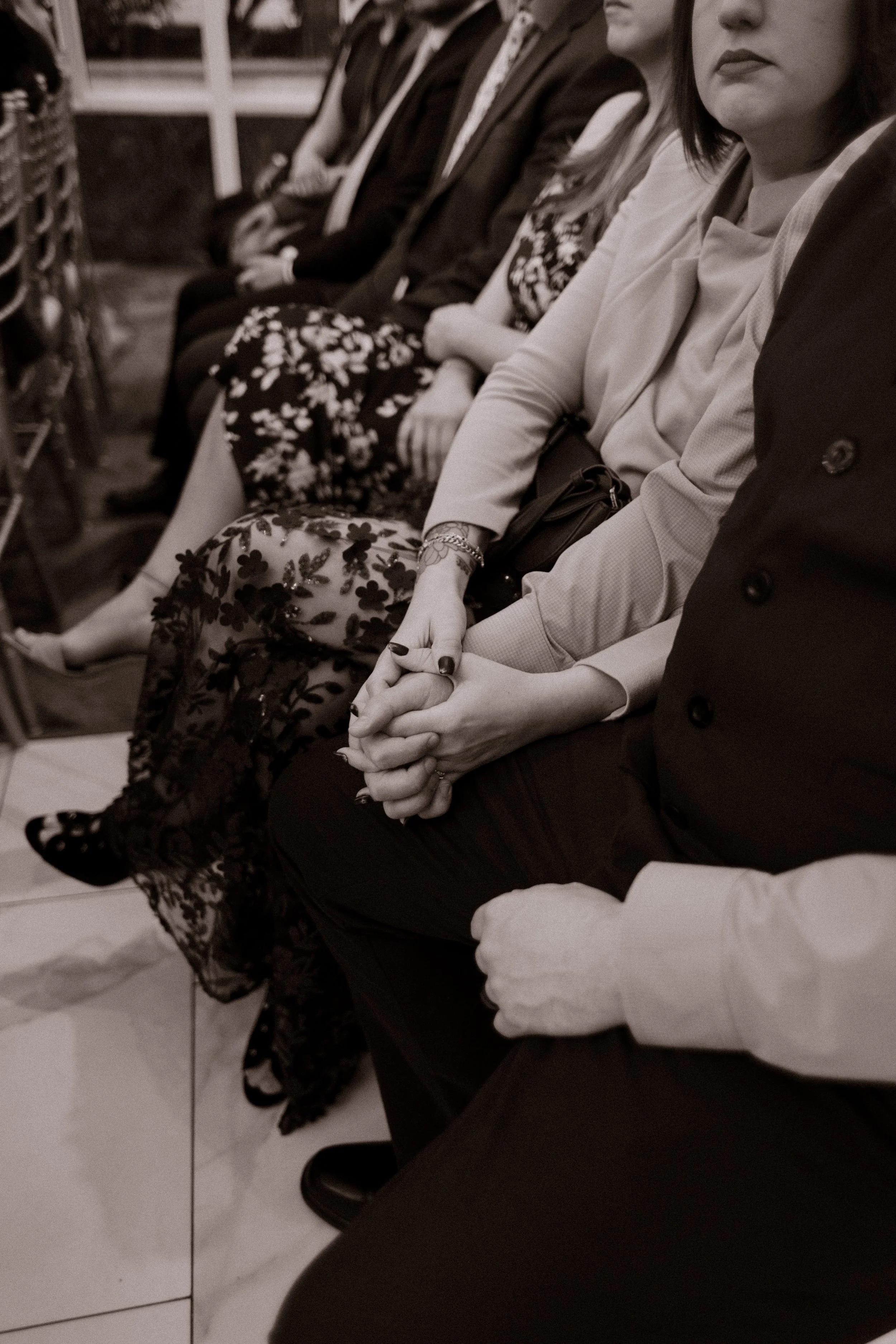 Wedding guests holding hands while seated together during an emotional ceremony moment