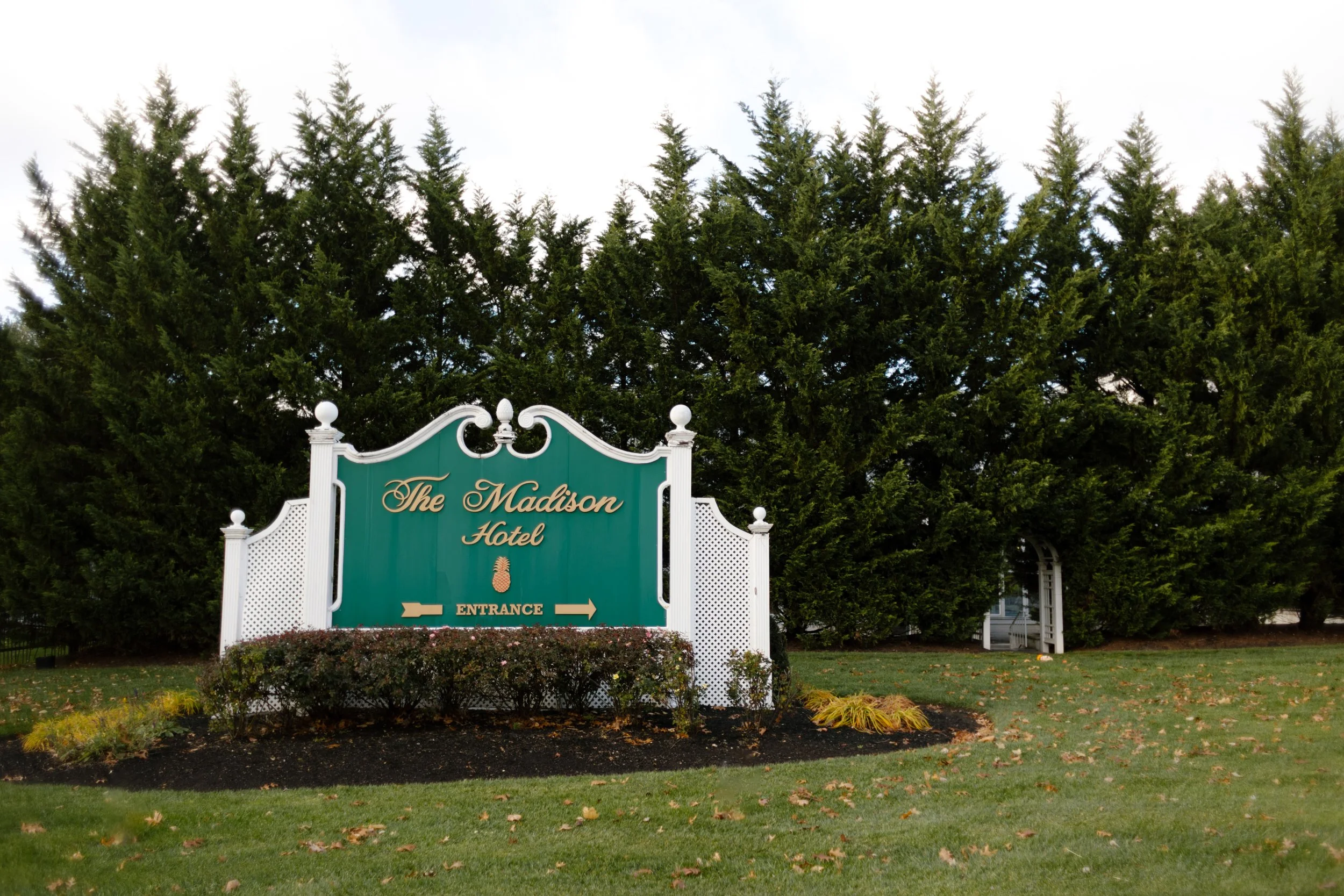 The Madison Hotel entrance sign surrounded by evergreen trees, a popular venue for a wedding in New York