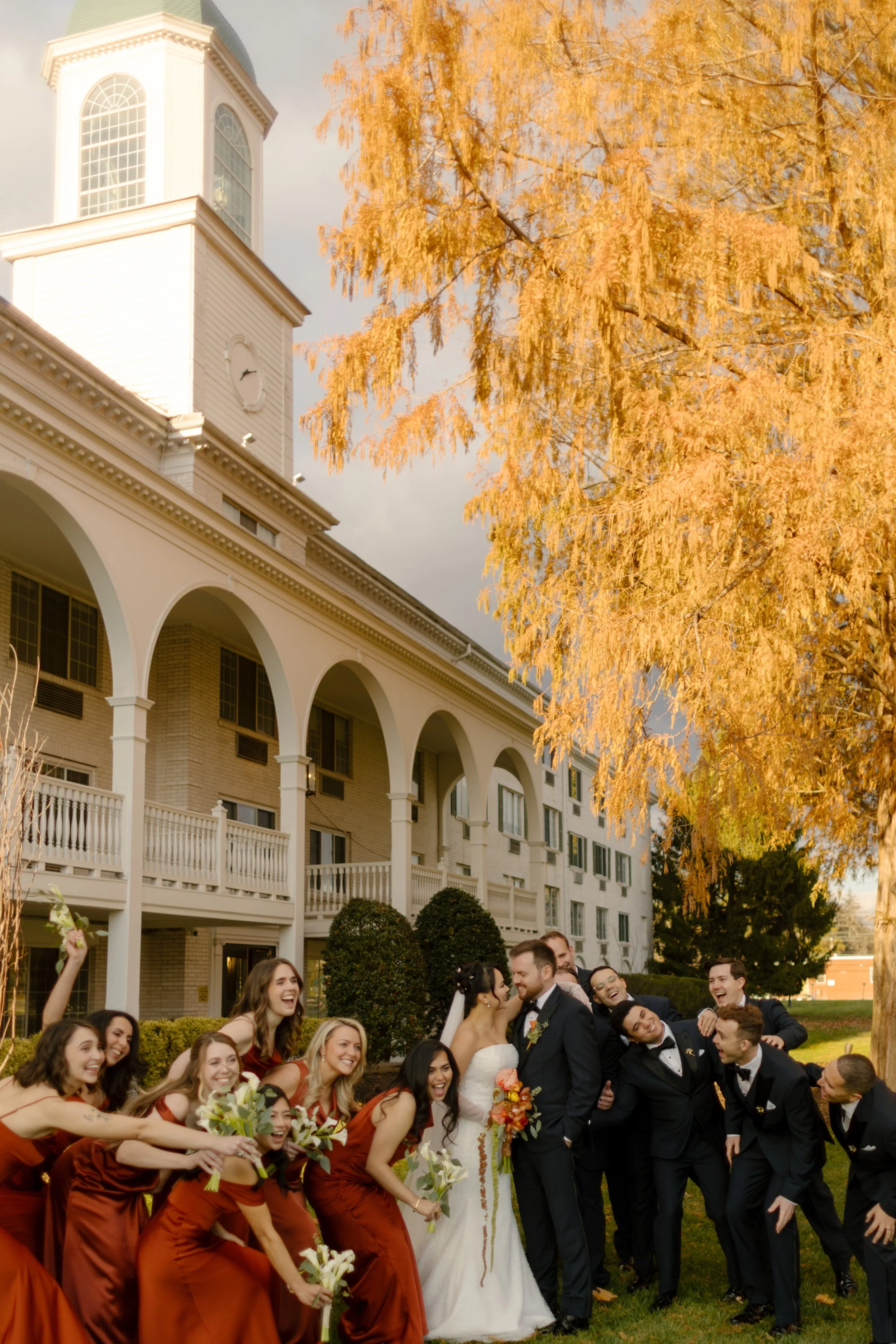 Wedding party celebrating outdoors beneath autumn foliage during a joyful wedding in New York group portrait