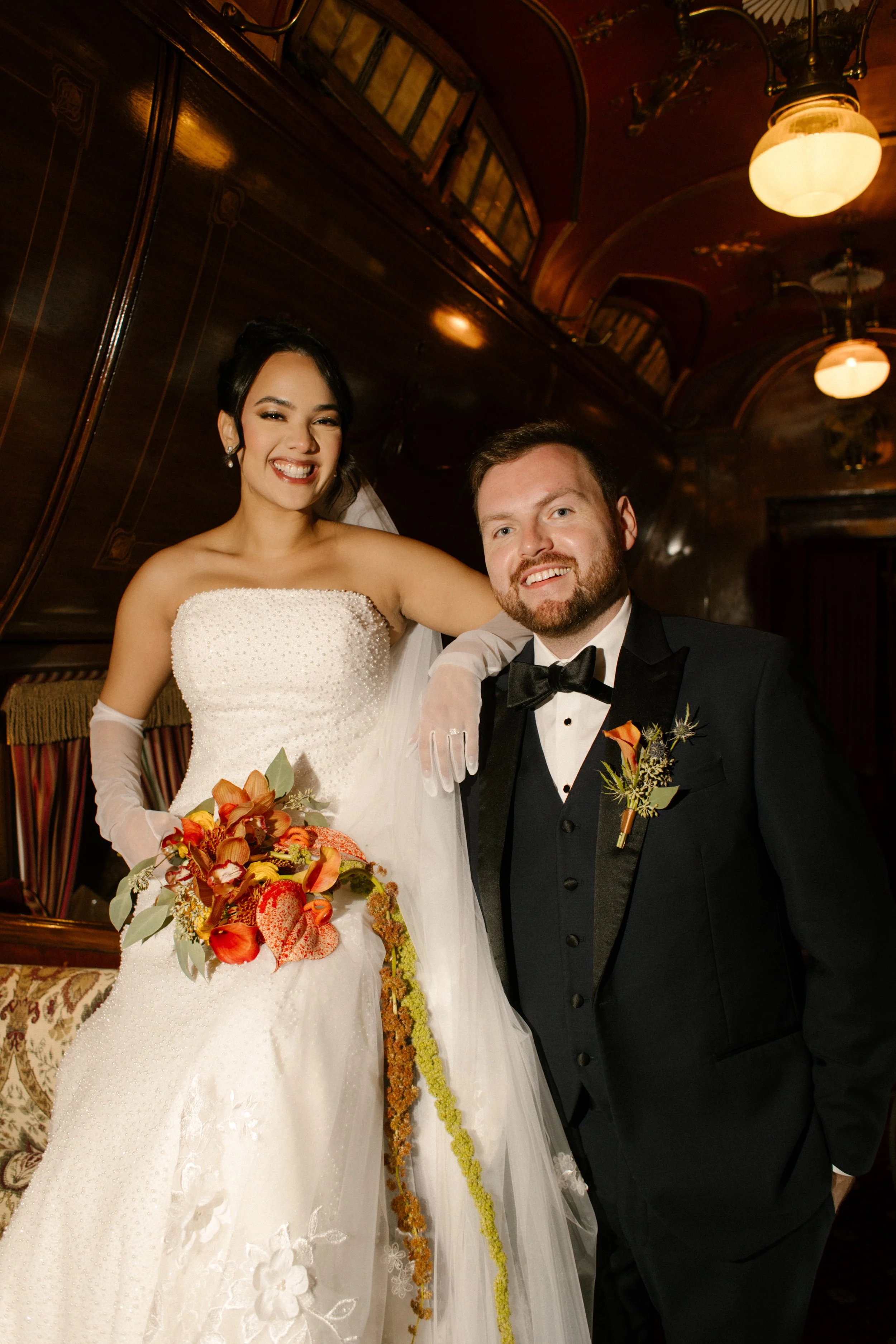 Bride and groom posing together inside a vintage railcar-inspired reception room during their wedding in New York