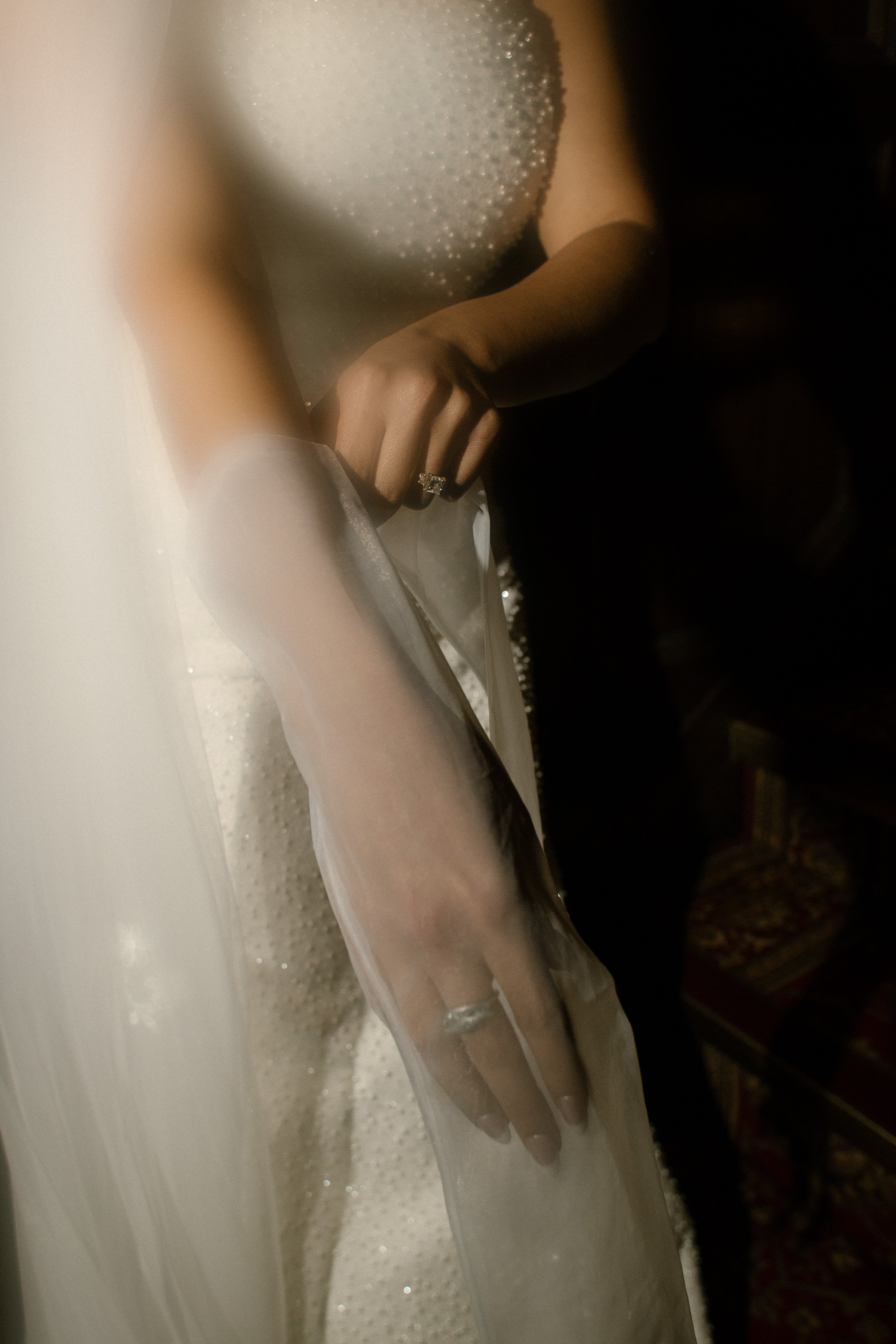 Close-up portrait of a bride’s wedding gown, veil, and engagement ring captured before a wedding in New York ceremony