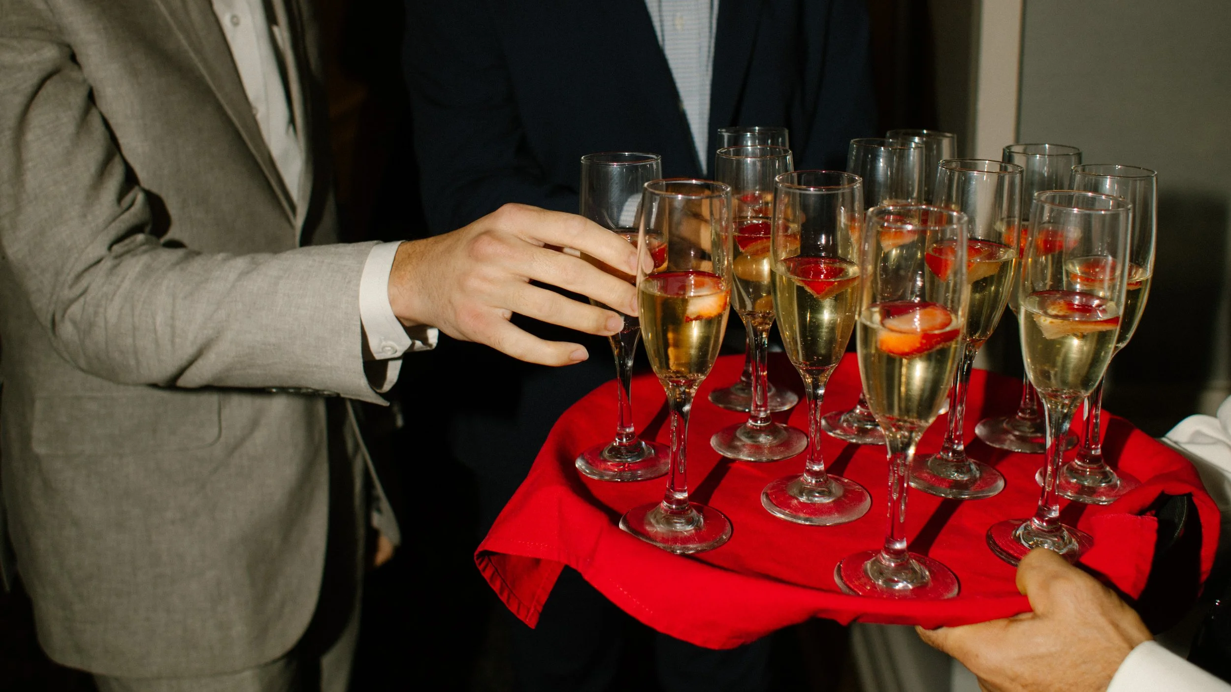 Guests reaching for champagne glasses during cocktail hour at an elegant wedding in New York reception