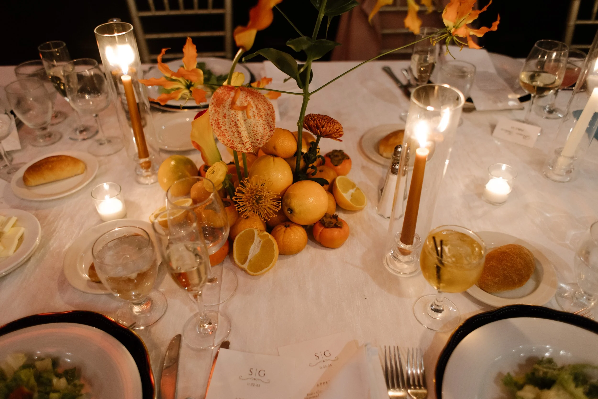 Autumn-inspired wedding reception centerpiece featuring citrus, florals, candles, and elegant table décor