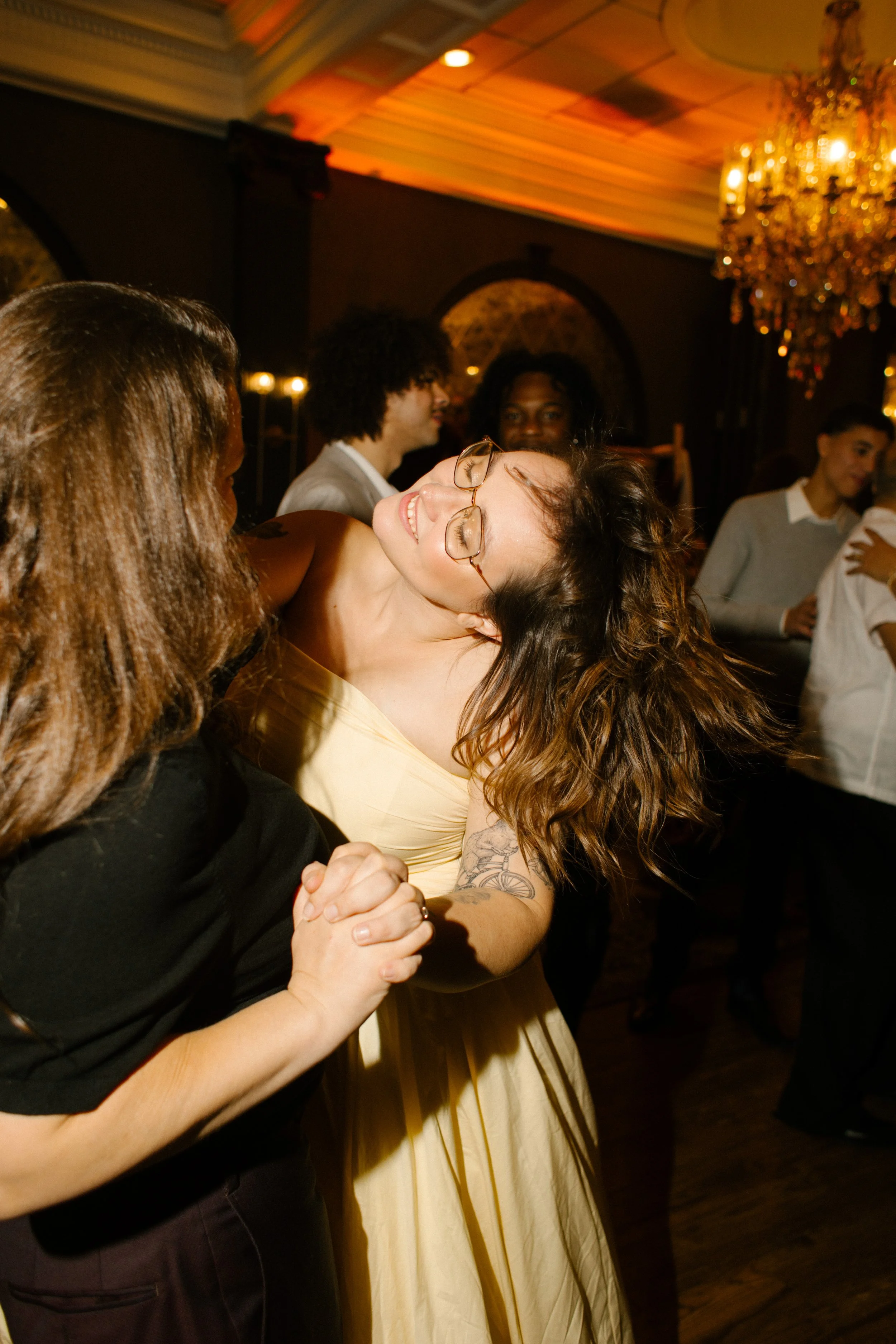 Guests dancing beneath chandelier lighting during a joyful wedding in New York reception party