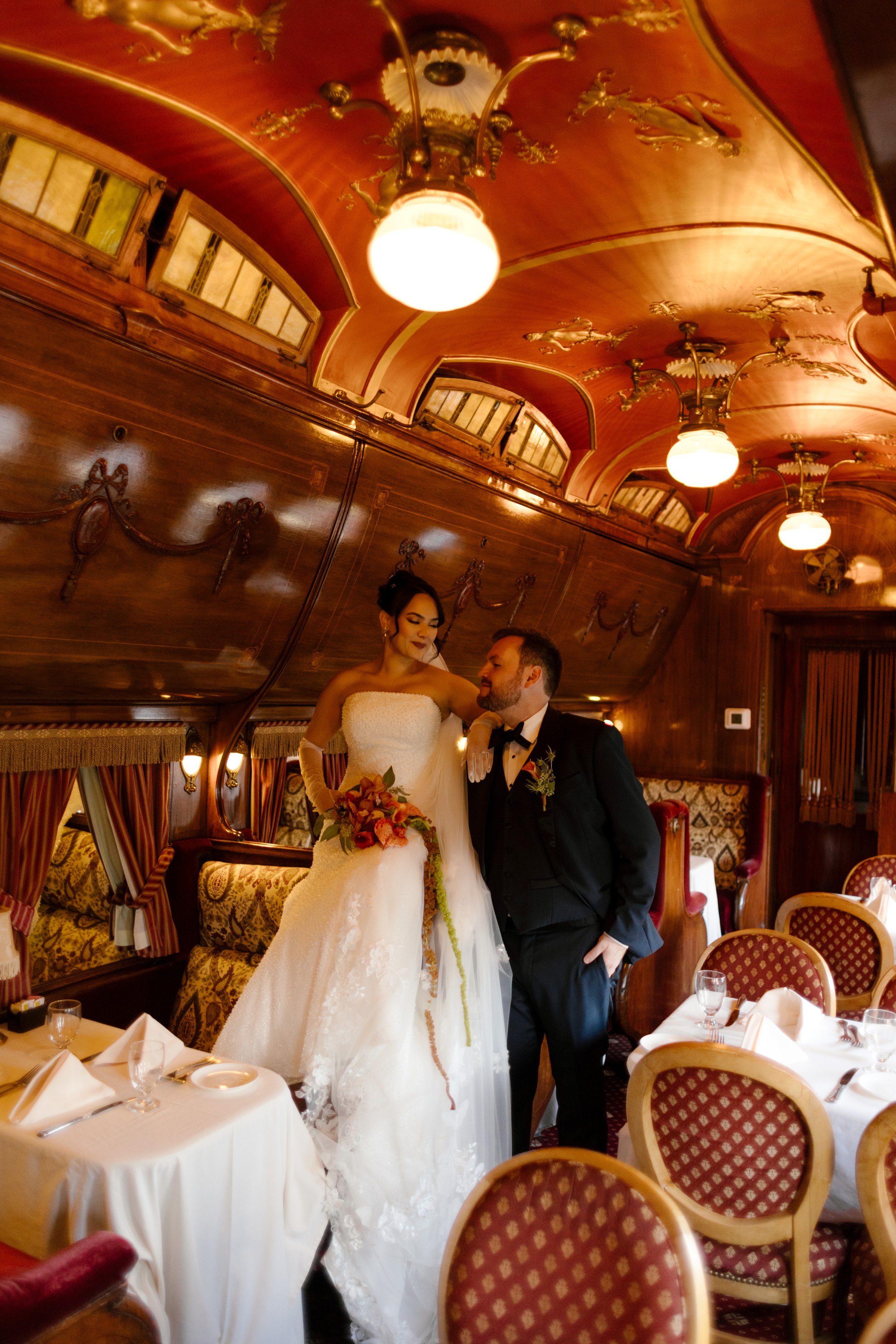 Bride and groom posing inside a vintage dining car during an elegant wedding in New York