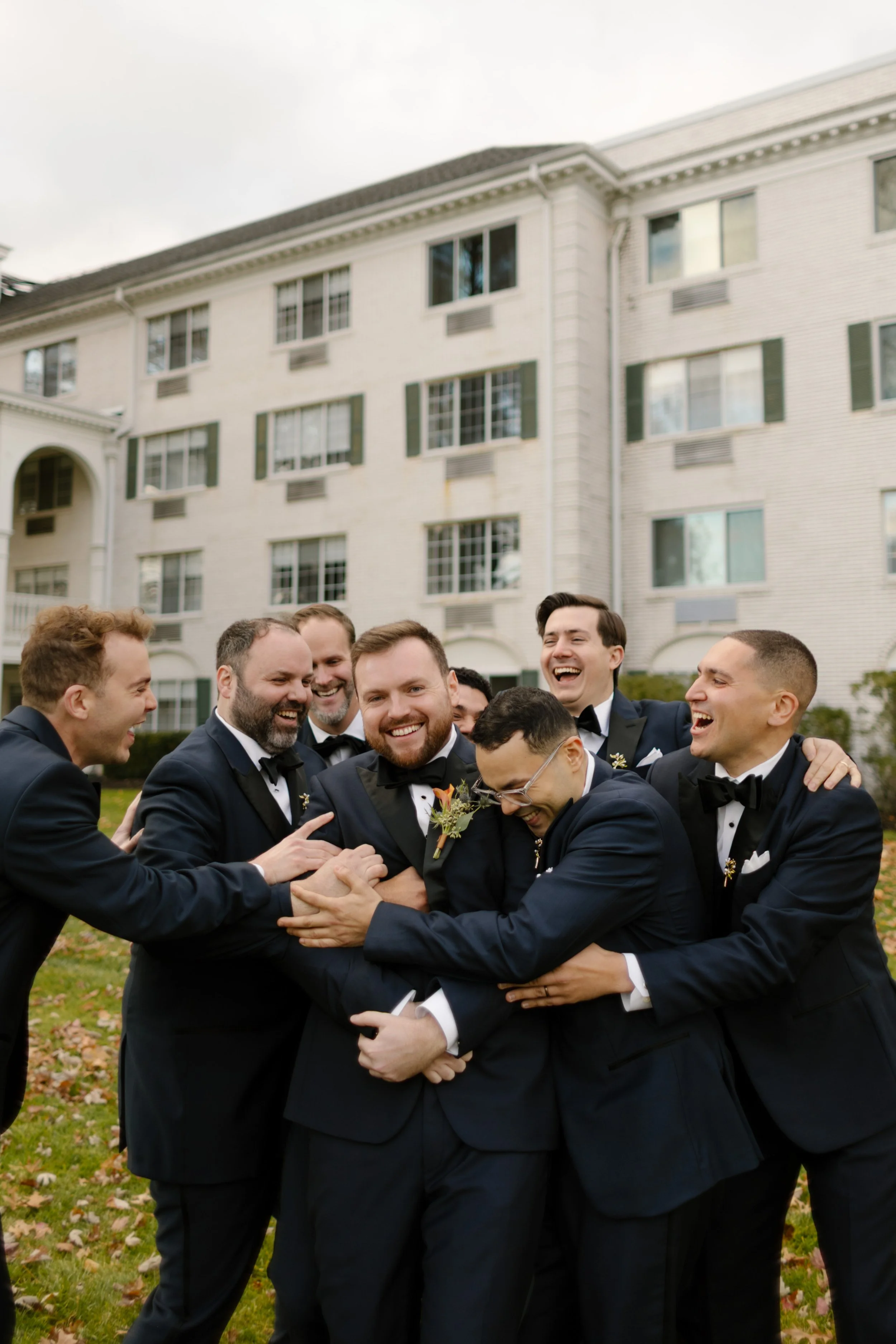 Groom laughing with groomsmen outside a historic hotel during a wedding in New York